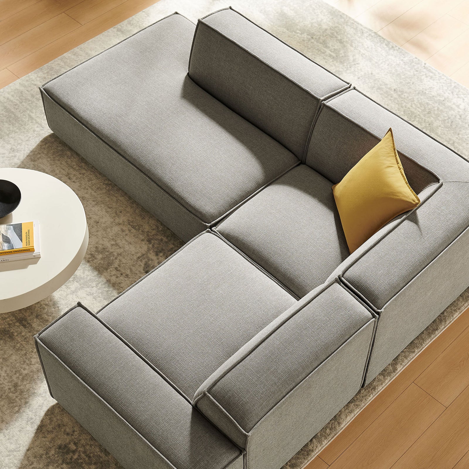 Cozy modular sectional anchored by a textured area rug, round table, and mustard accent pillow. || EEI-7419-PEW || top_angle_room