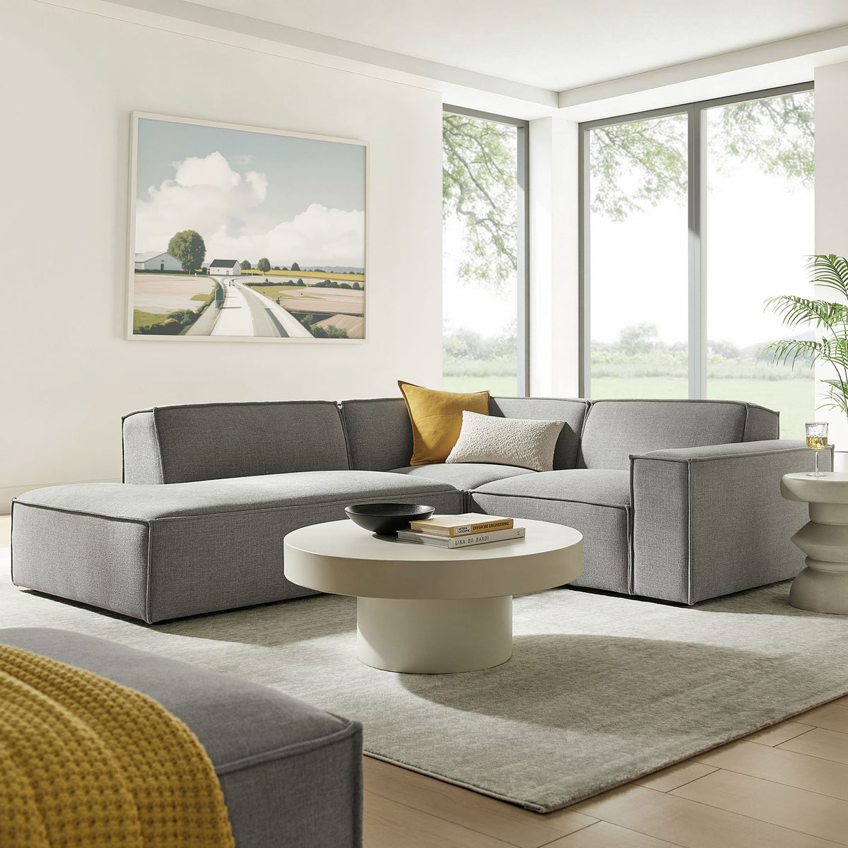 Left-facing pewter sectional arranged in a sunlit living room with neutral rug and round coffee table. || EEI-7419-PEW || front_angle_room