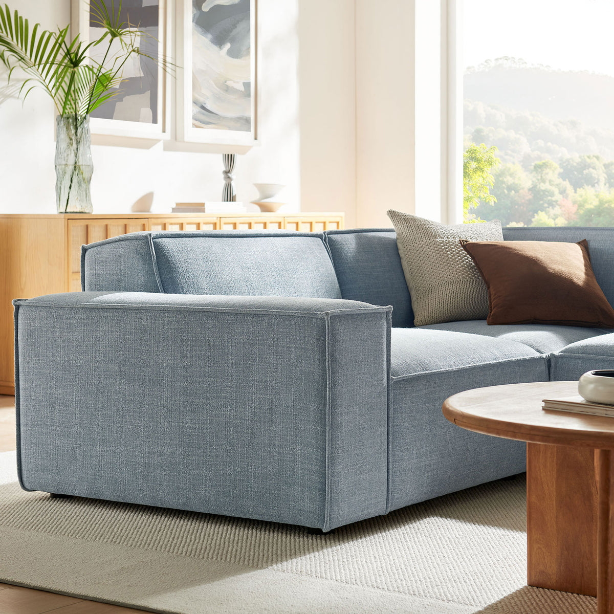 Generous armrest and chaise section in sky blue fabric, accented with pillows for laid-back comfort || EEI-7421-SKY || front_angle_partial_room