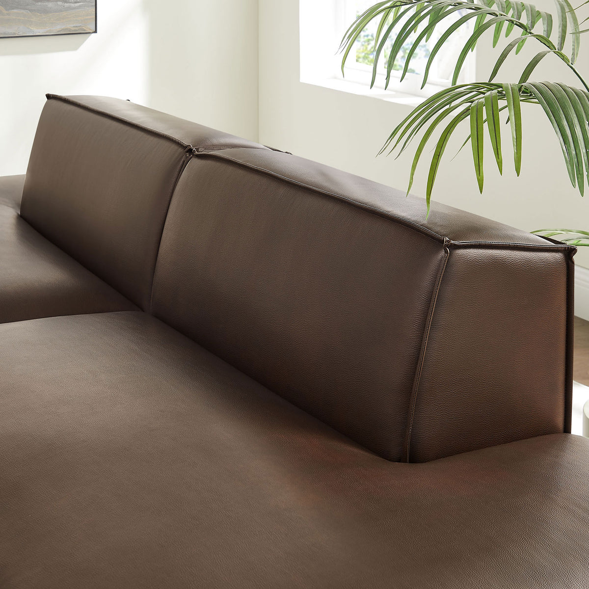 Detail of the low-profile back cushions showing smooth vegan leather texture and refined French piping || EEI-7424-ESP || detail_room