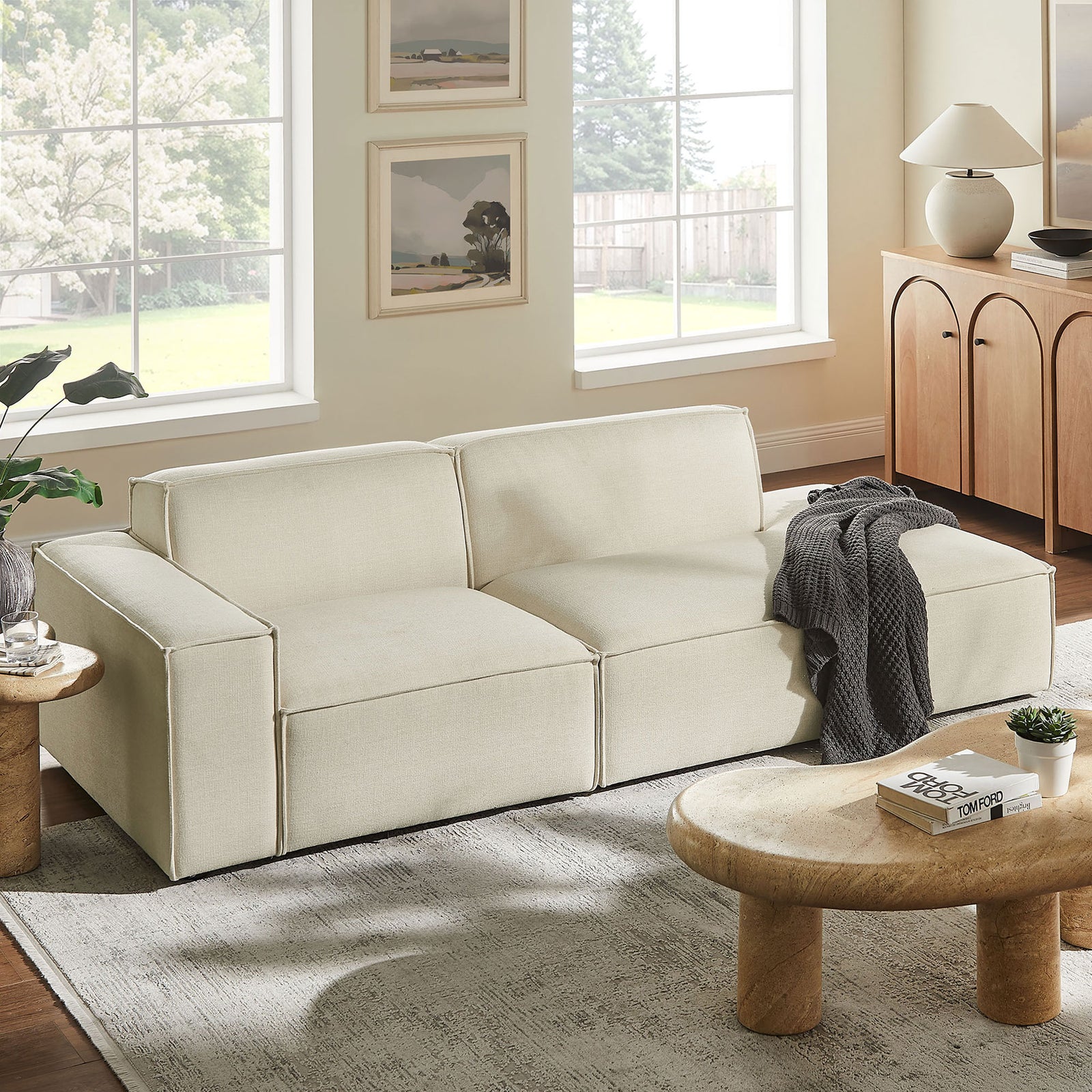 Ecru modular loveseat styled in a bright living room with soft rug and rounded wood coffee table || EEI-7425-ECR || front_angle_room