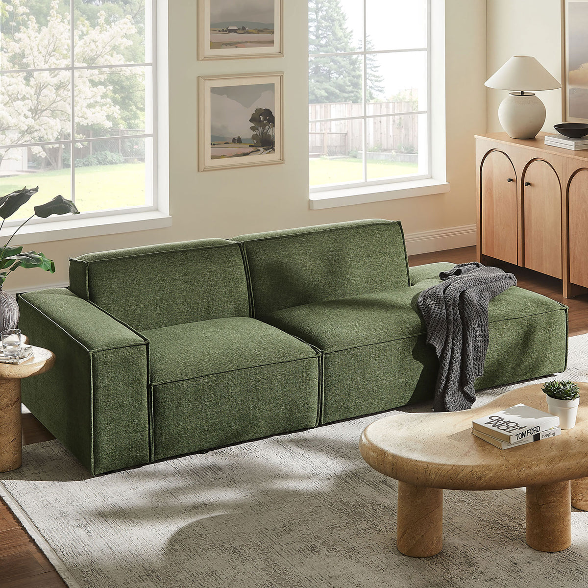 Foliage green modular loveseat styled in a bright living room with cozy rug, wood tables, and throw || EEI-7425-FOL || front_angle_room