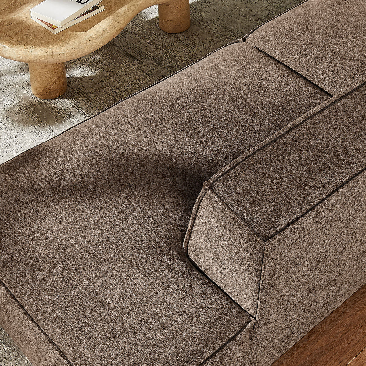 Soft mocha seat cushions with textured weave beside a sculpted wood coffee table and rug || EEI-7425-MOC || detail_room