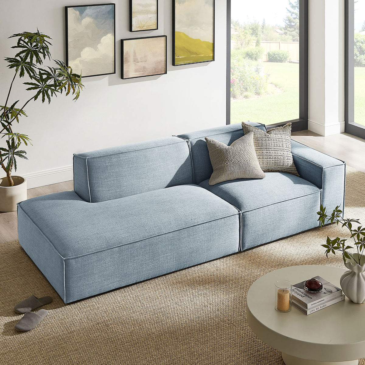 Sky blue modular loveseat softens a sunny living room with generous chaise, accent pillows, and tailored lines || EEI-7427-SKY || front_angle_room