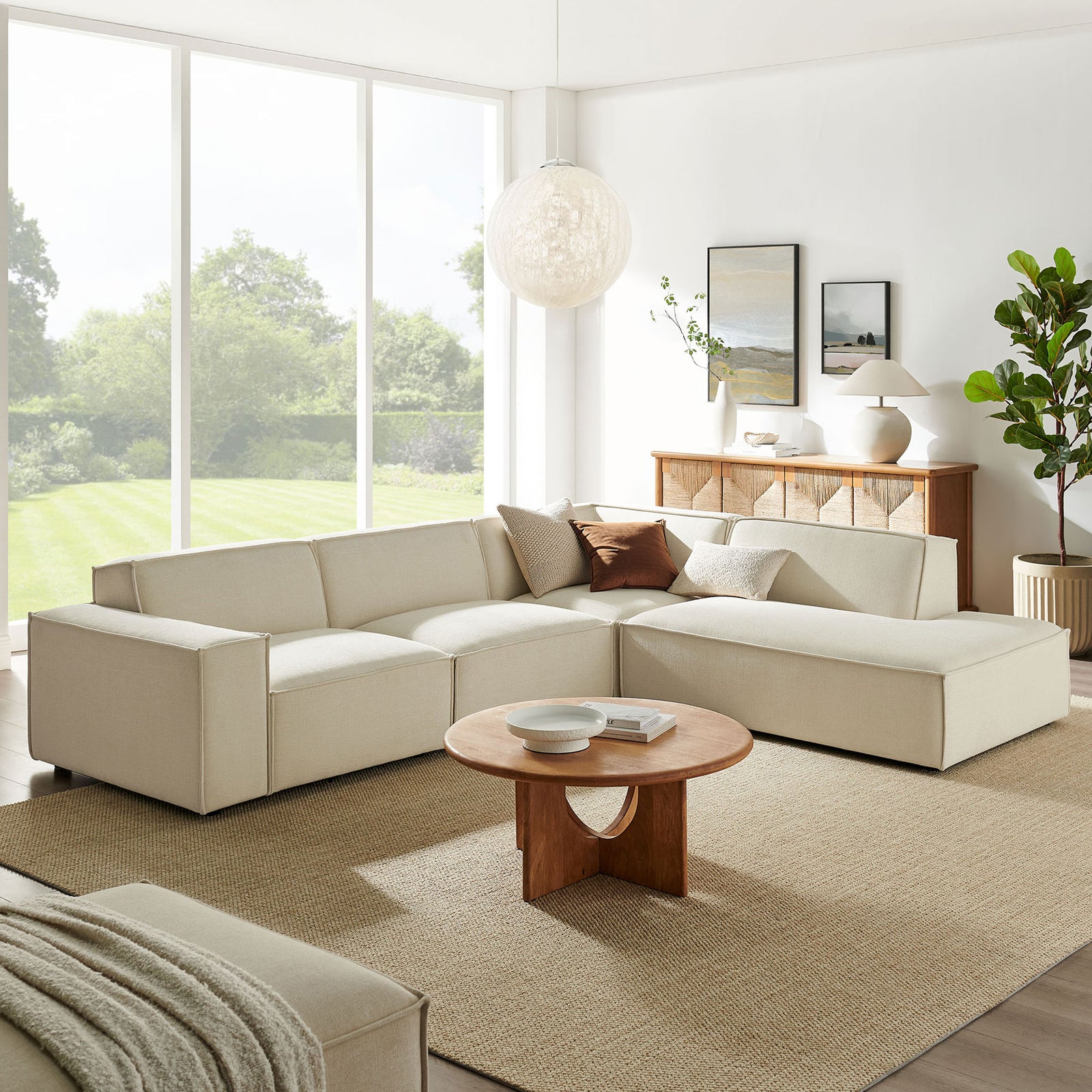 Restore ecru modular sectional arranged in an airy living room with round wood coffee table and greenery || EEI-7429-ECR || front_angle_room