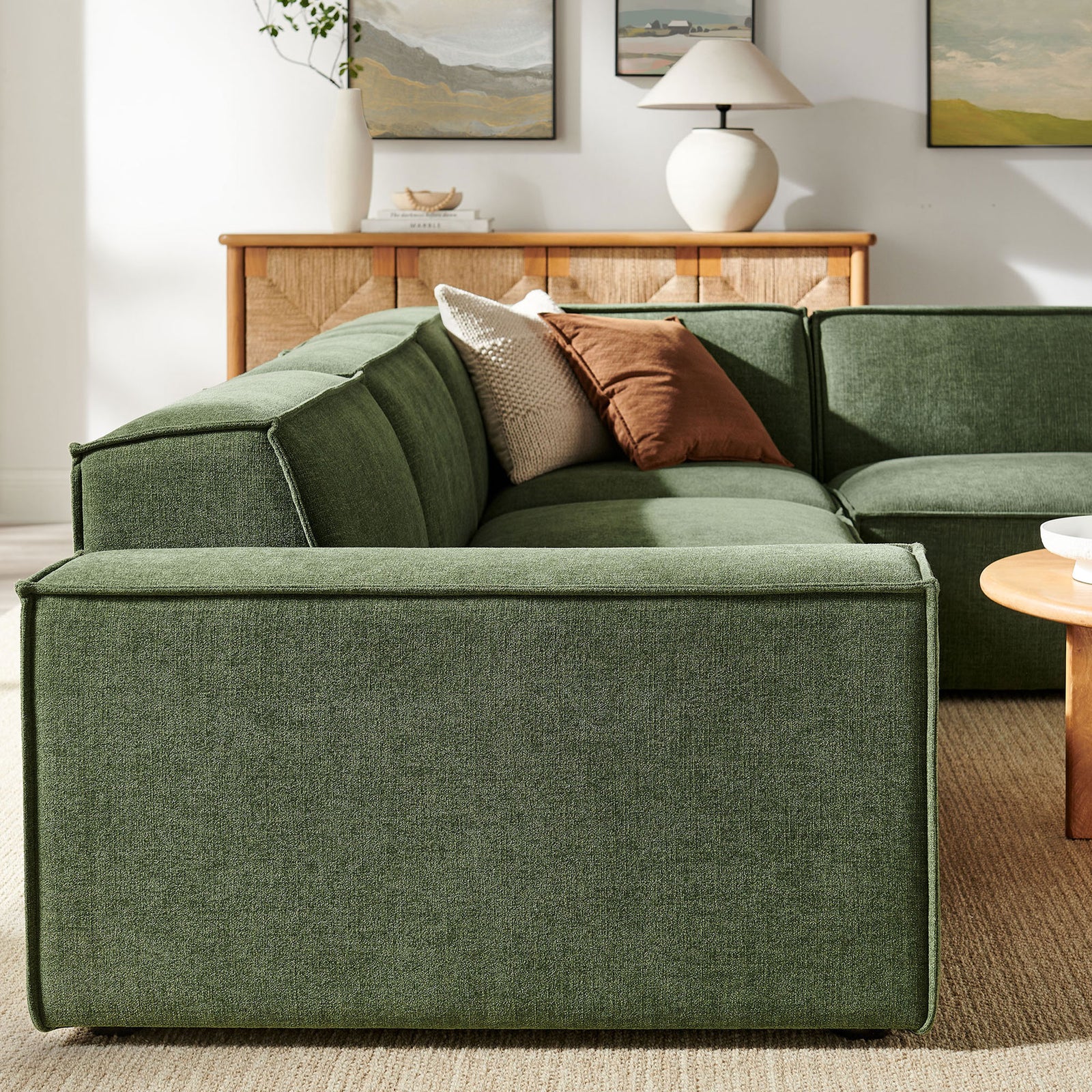 Restore foliage green modular sectional back cushions and clean seams paired with warm wood credenza and artful decor || EEI-7429-FOL || detail_room