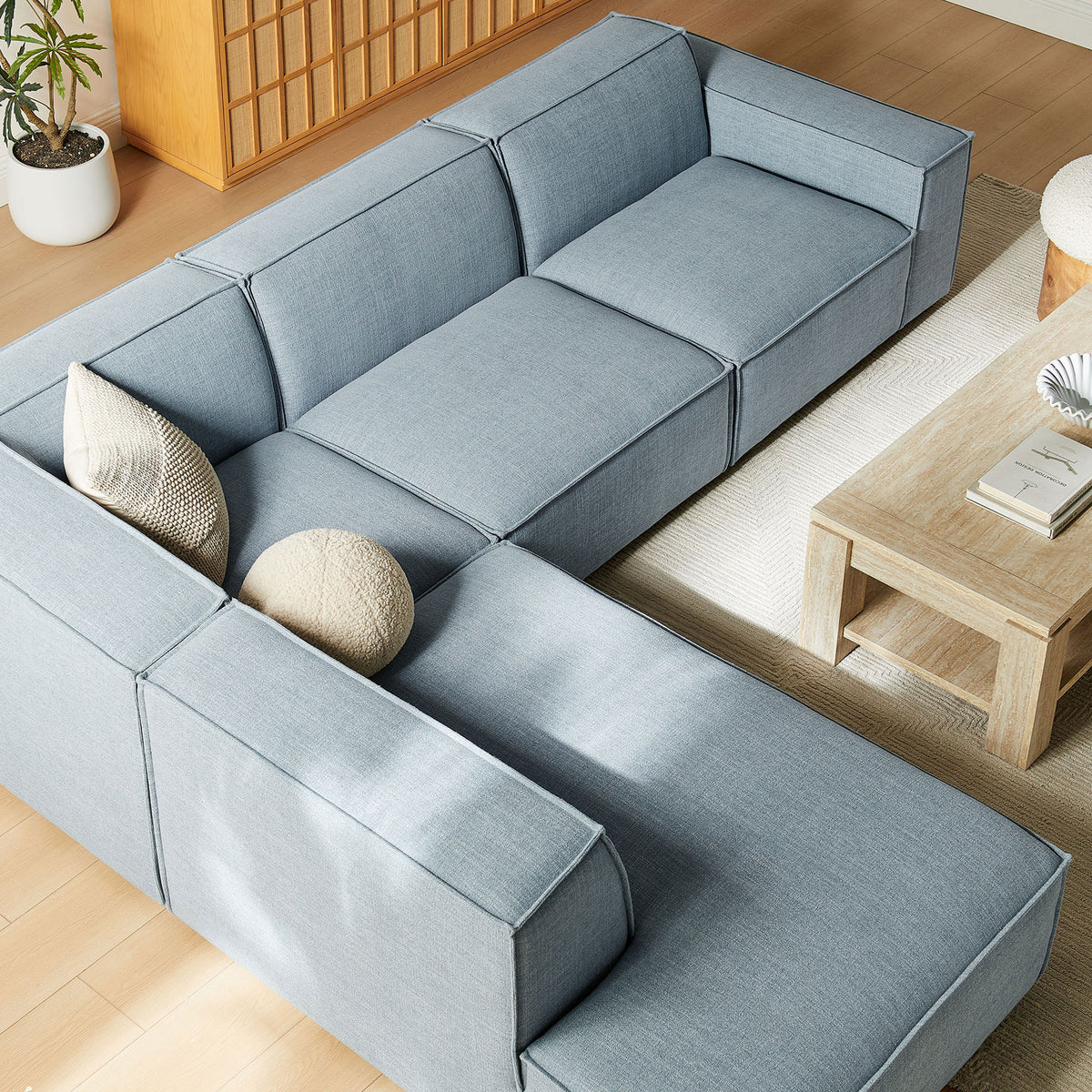 Sky blue L-shaped sectional arranged around a light wood coffee table on a textured area rug || EEI-7431-SKY || detail_room