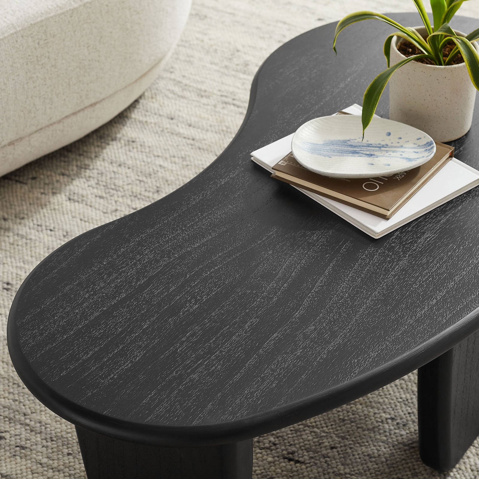 Textured black wood grain surface styled with books and a plant on the curved tabletop || EEI-7437-BLK || detail_room