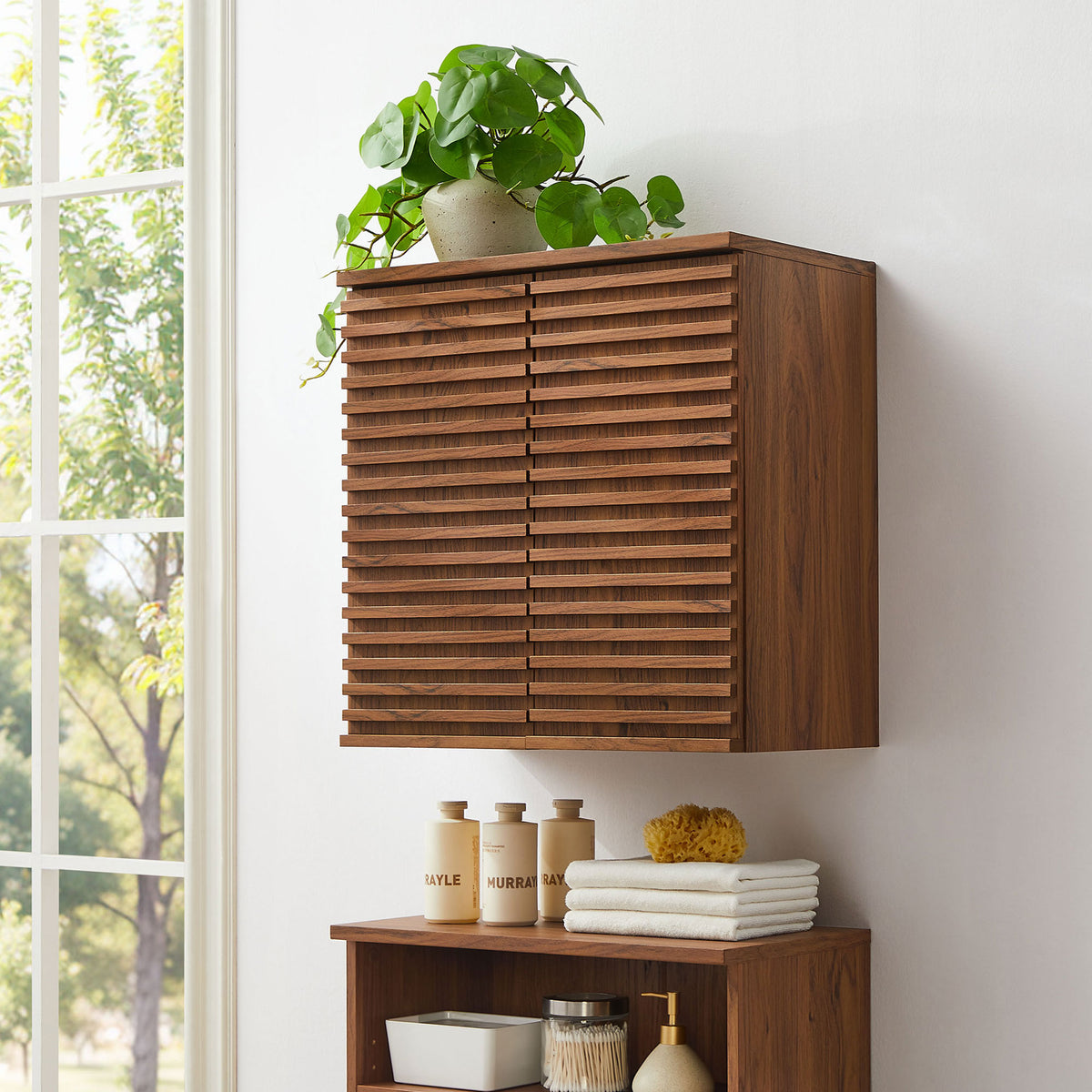 Streamlined wall cabinet elevates bath decor with mid-century slatted doors and a warm walnut tone. || EEI-7438-WAL || front_angle_room