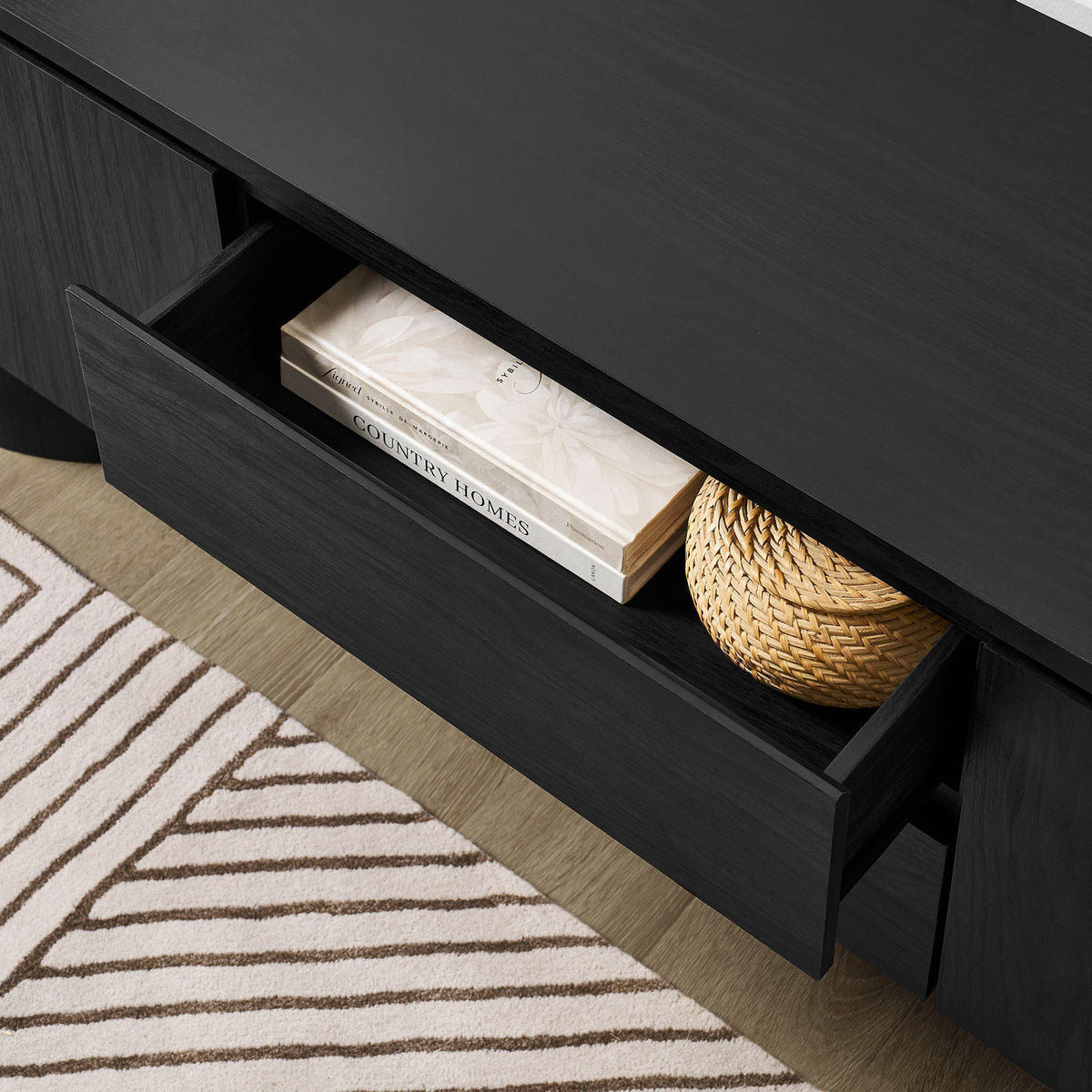Open drawer of the black TV cabinet styled with books and a basket in a modern living room || EEI-7440-BLK || storage_open_room