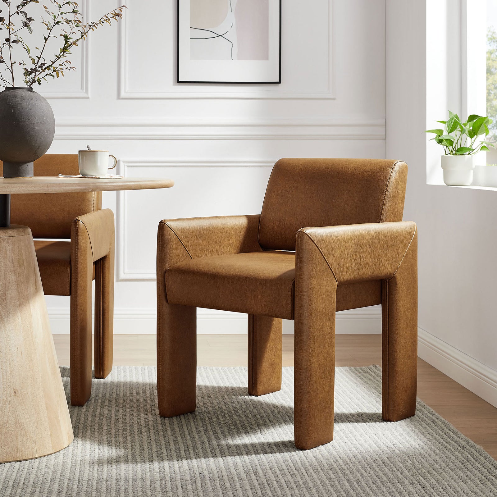 Canyon vegan leather dining armchair styled at a modern table with textured rug and greenery || EEI-7443-CAN || front_angle_room