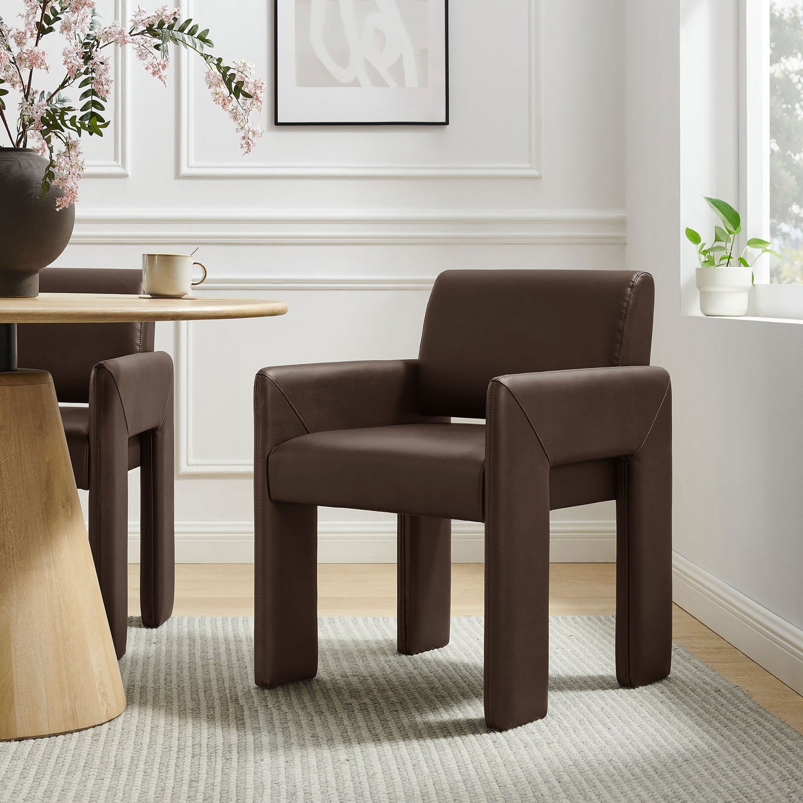 Modern espresso vegan leather dining armchair styled beside a round wood table in an airy dining nook. || EEI-7443-ESP || front_angle_room