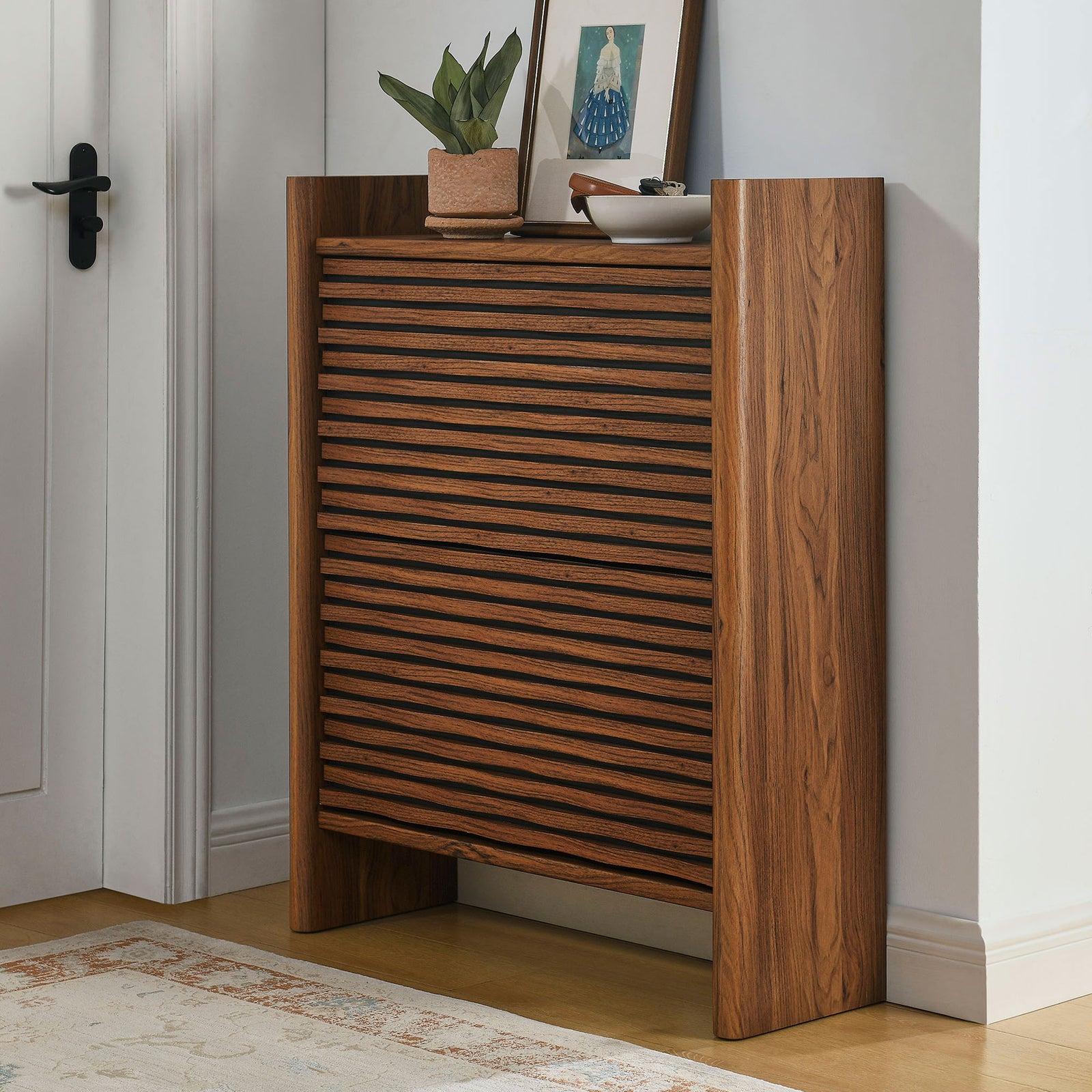 Walnut wave front shoe cabinet styled in an entryway with decor on the top and rug on the floor || EEI-7447-WAL || front_room