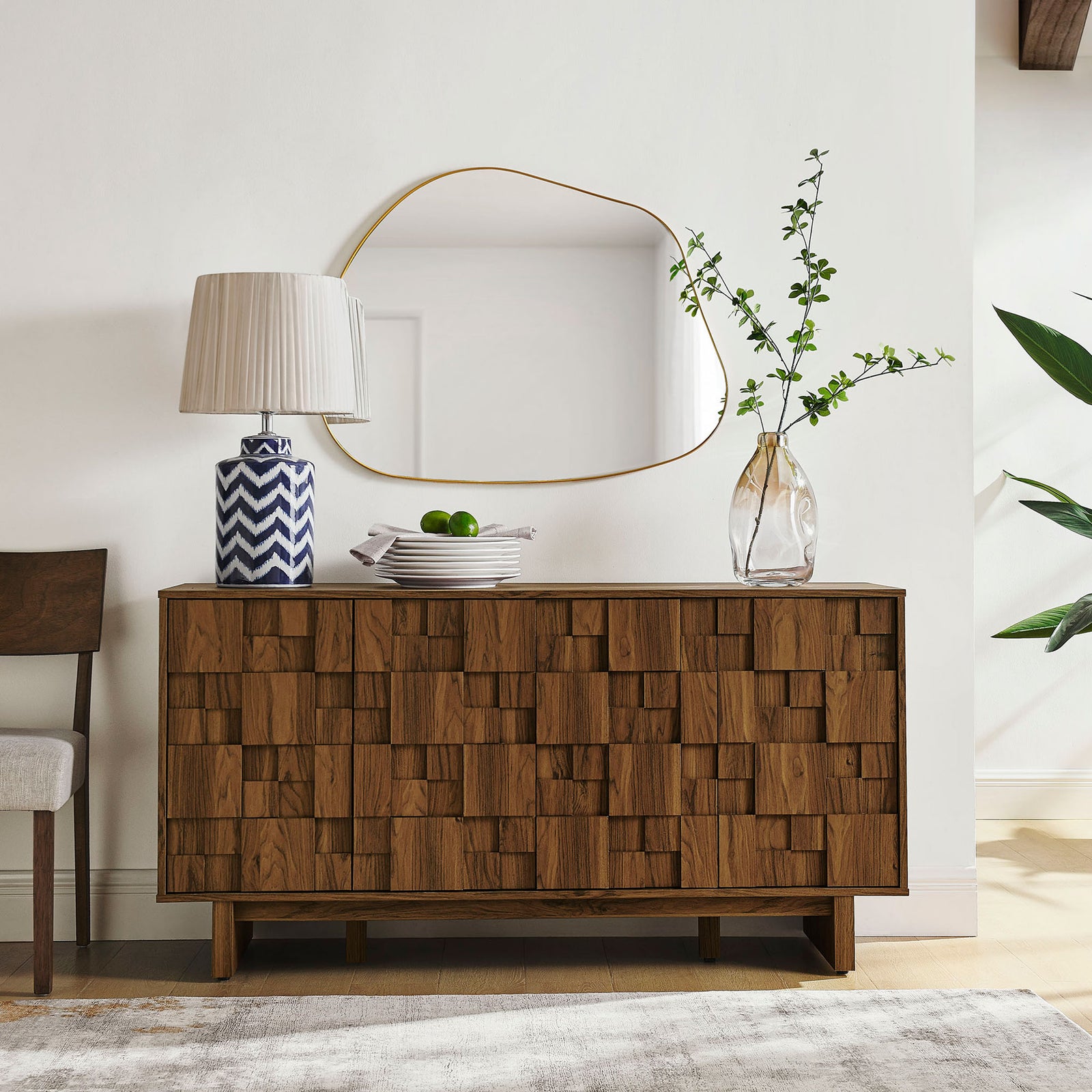 Walnut geometric sideboard styled in a modern room with lamp, mirror, and greenery accents || EEI-7448-WAL || front_angle_room