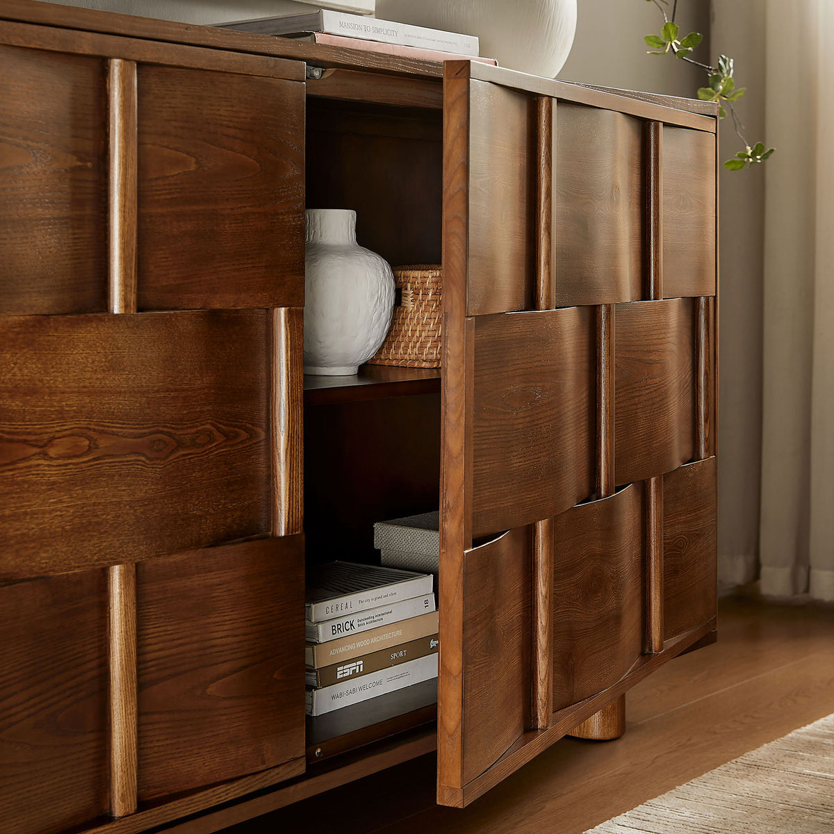 Walnut cabinet door opens to reveal roomy shelves styled with books, baskets, and decorative accents || EEI-7452-WAL || storage_open_room