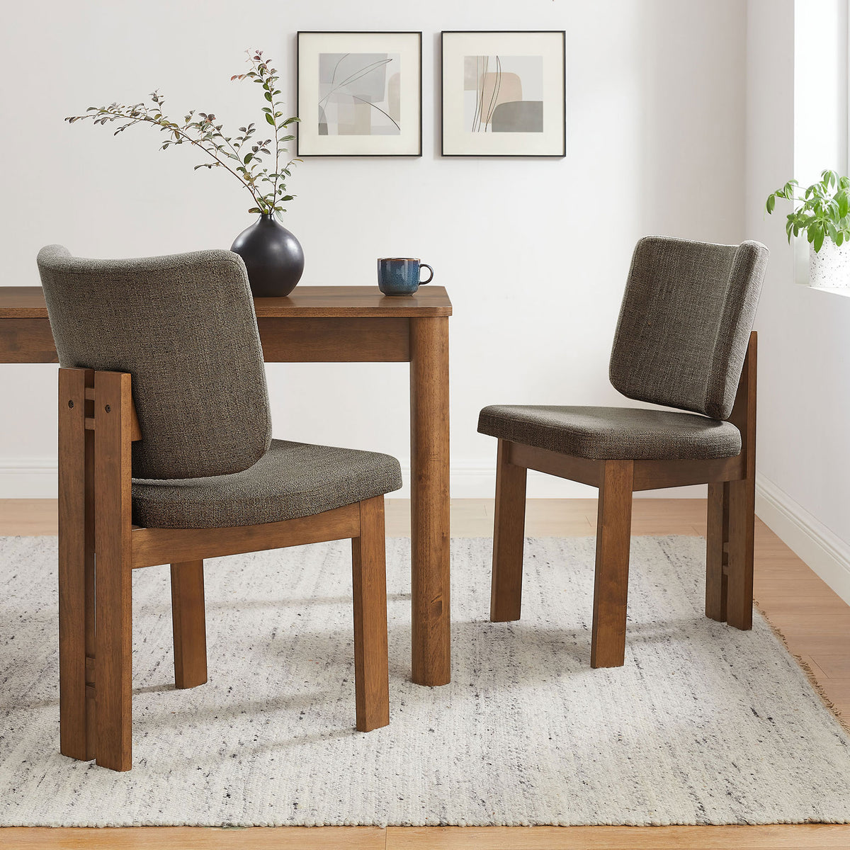 Pair of taupe upholstered dining chairs around a wooden table on a textured rug in a bright dining nook || EEI-7465-TAU || front_angle_multi_room