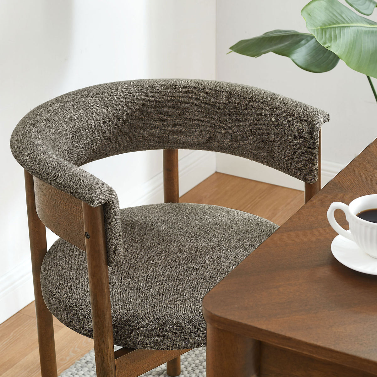 Taupe curved dining chair styled beside a warm wood table in a bright dining nook || EEI-7467-TAU || front_angle_room