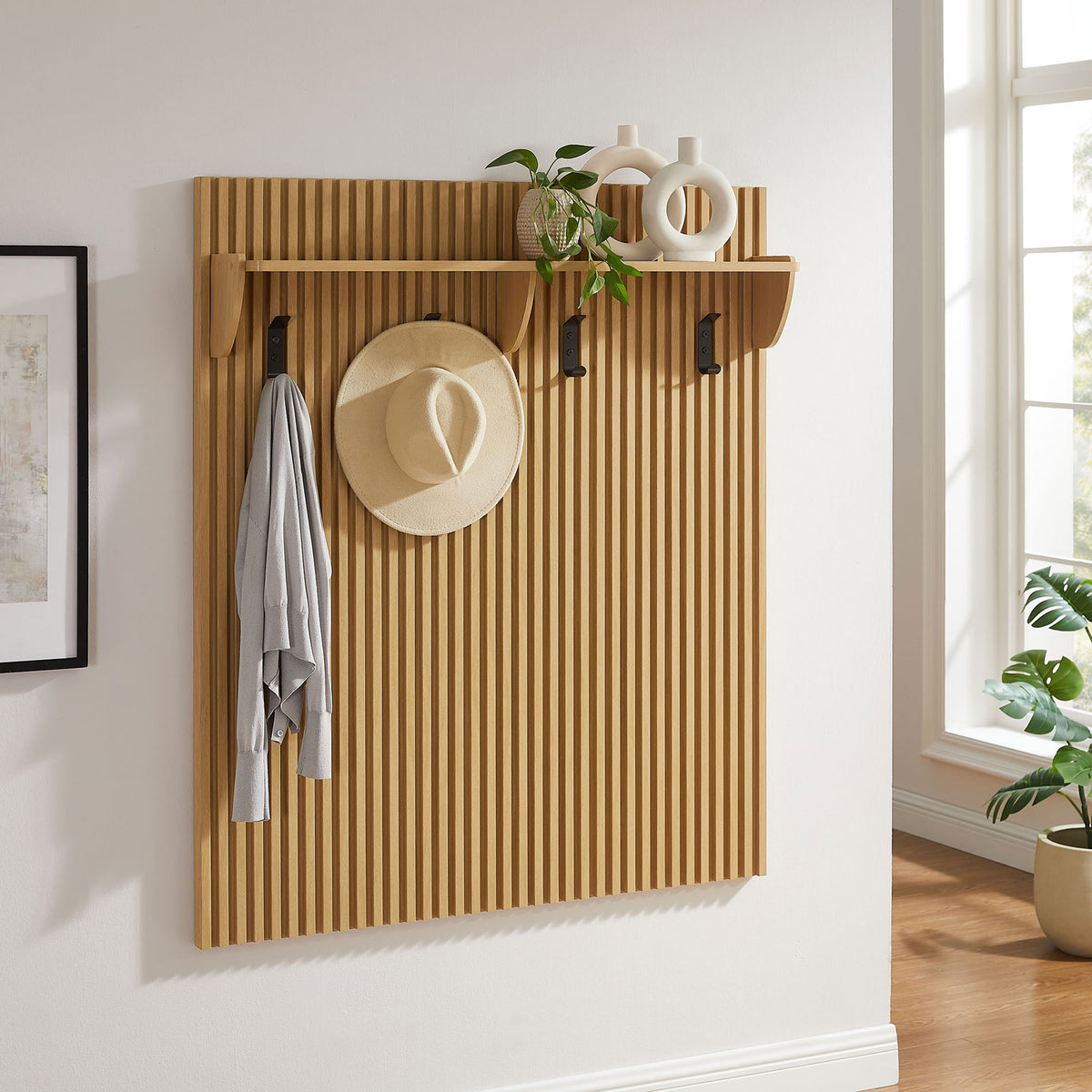 Fluted coat rack panel adds warmth and storage with top shelf and four black hooks in light oak || EEI-7472-OAK || front_angle_room