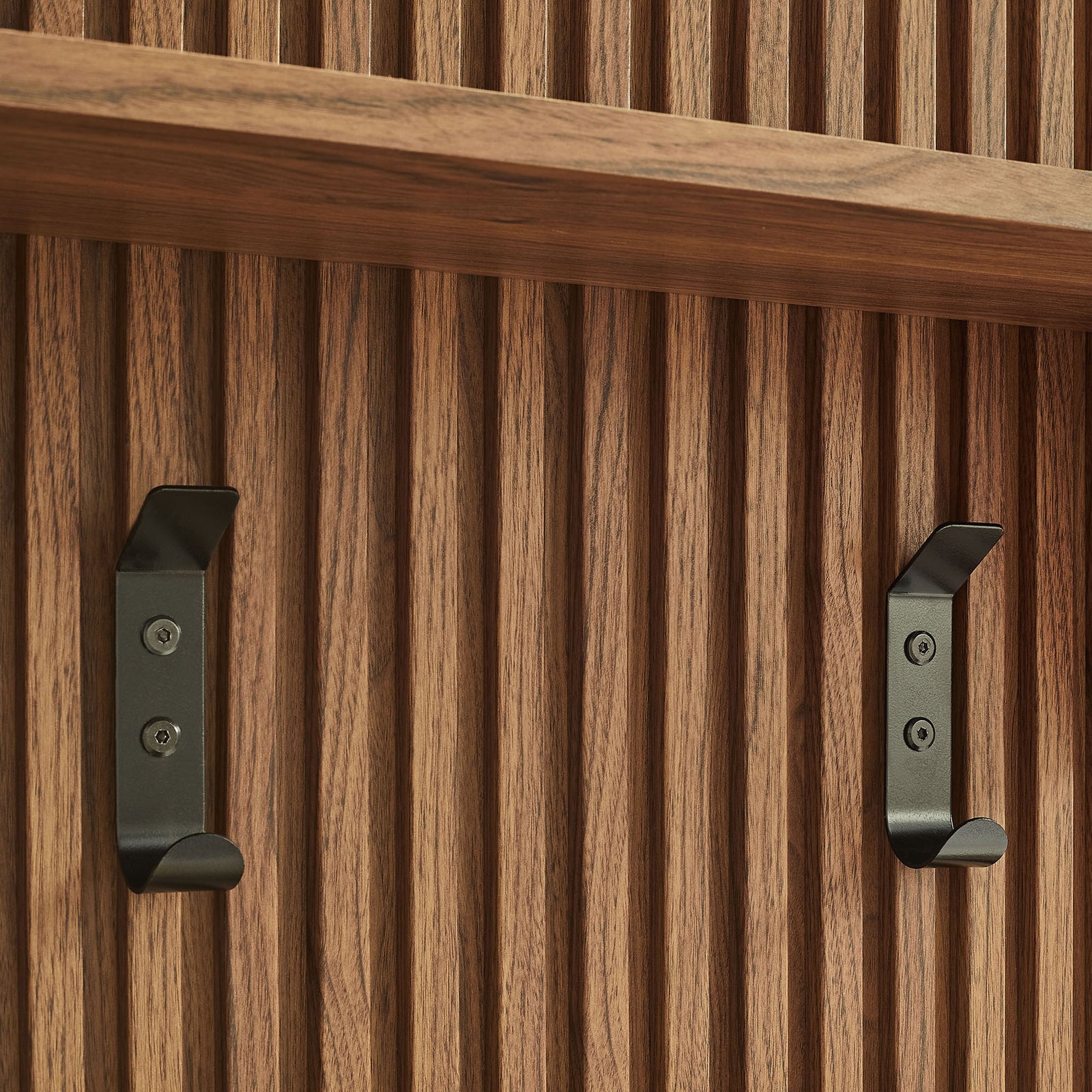 Matte black coat hooks stand out against the vertical fluted walnut slats || EEI-7472-WAL || storage_studio