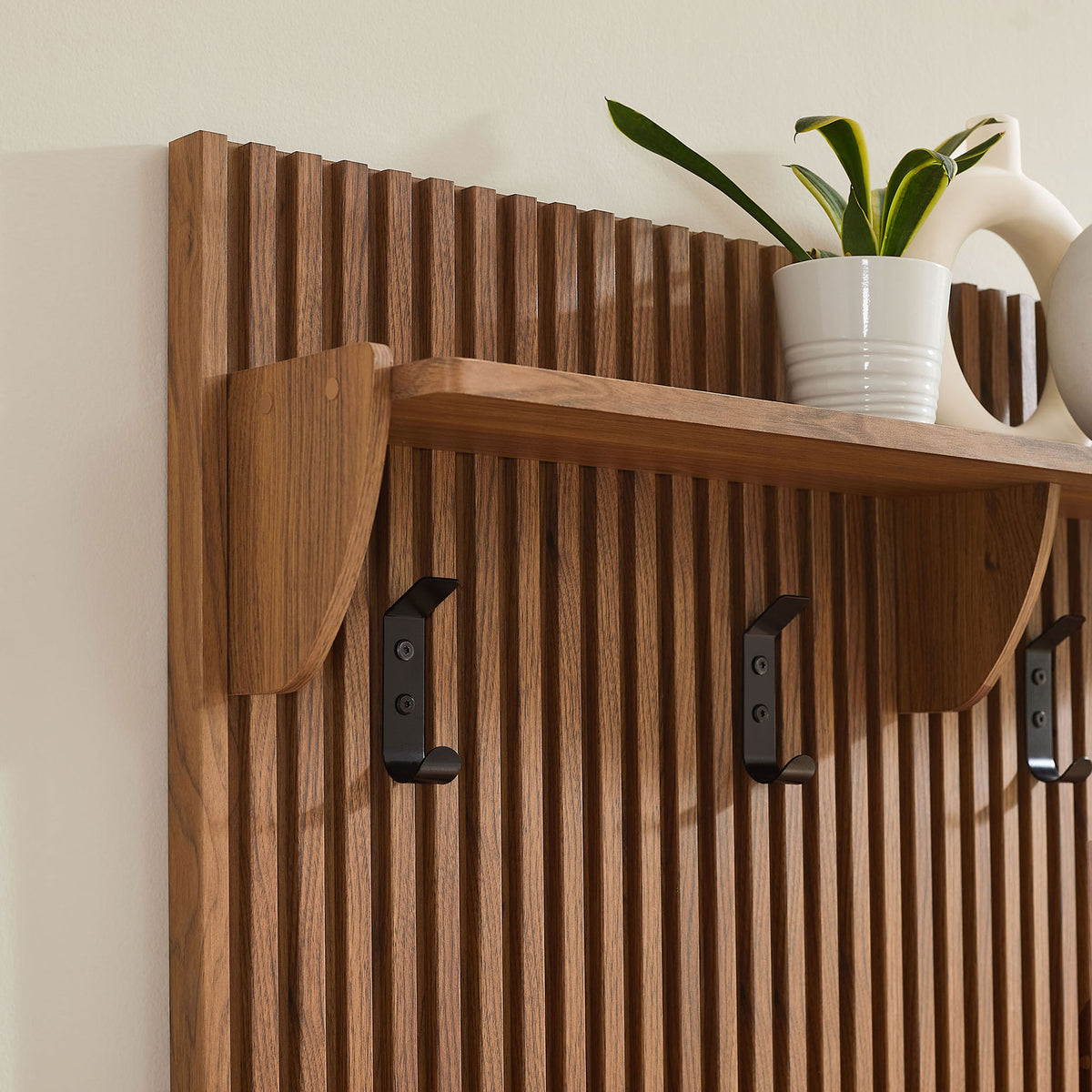 Walnut slatted panel with shelf and hooks adding warmth against a light wall || EEI-7472-WAL || storage_room