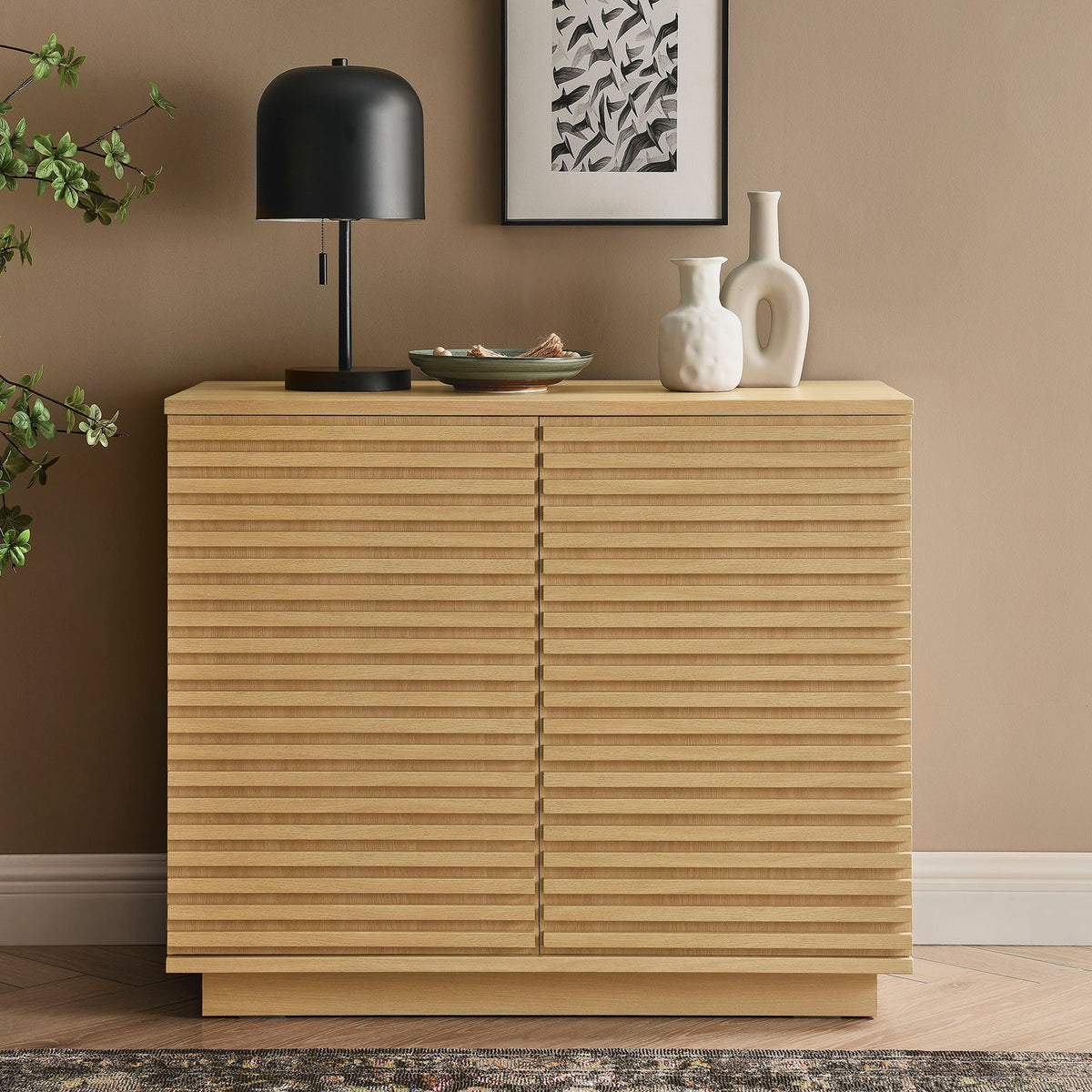 Oak fluted accent cabinet styled with decor in a warm modern living room setting || EEI-7476-OAK || front_angle_room