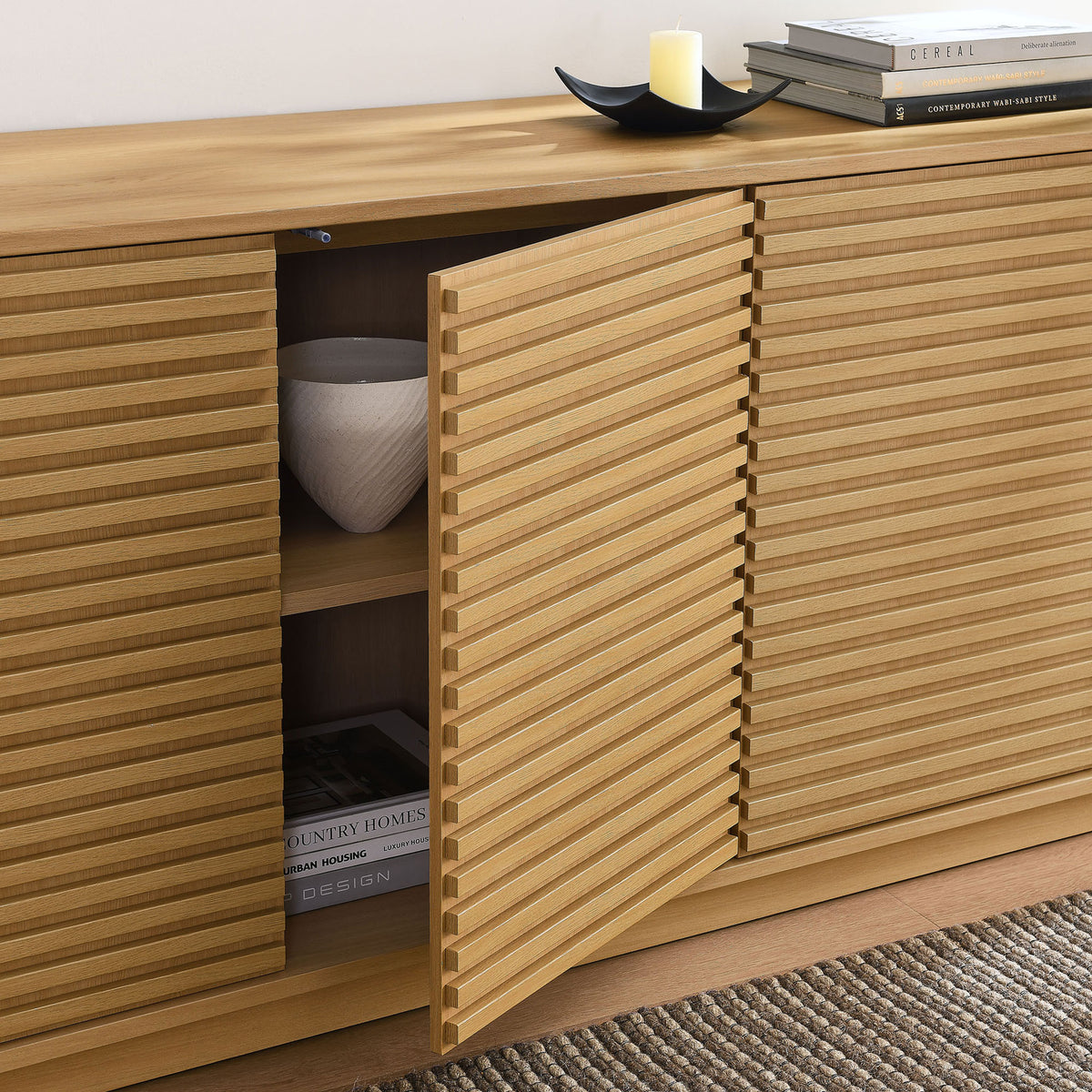 Open fluted door reveals roomy shelving for decor and books, styled in a warm modern living space || EEI-7477-OAK || storage_open_room