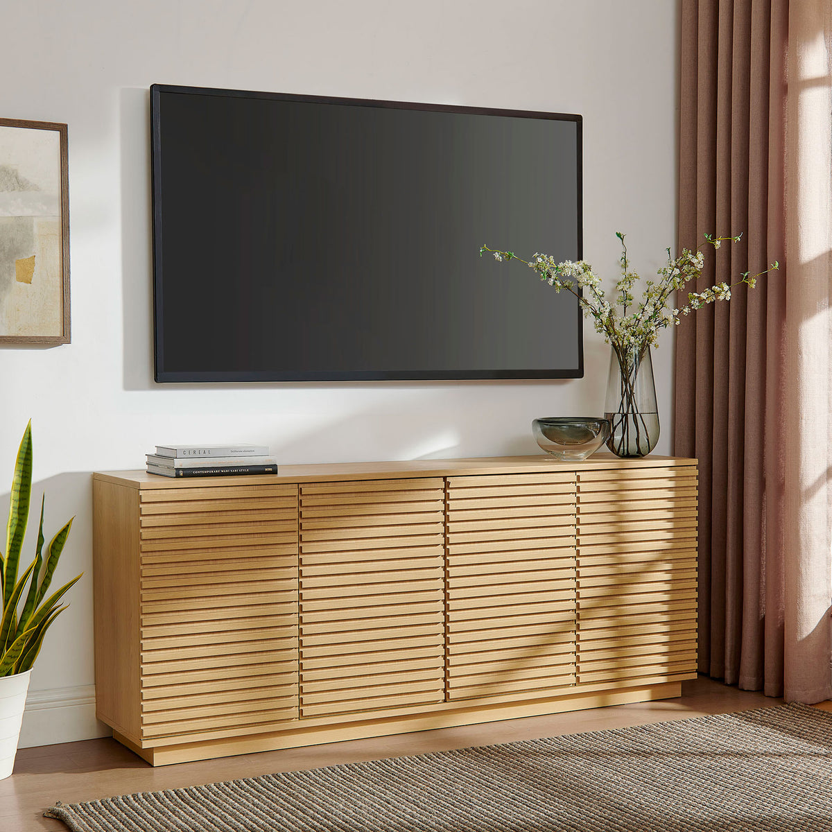 Fluted oak sideboard anchors a media wall beneath a mounted TV with plants and sculptural decor || EEI-7477-OAK || front_angle_room