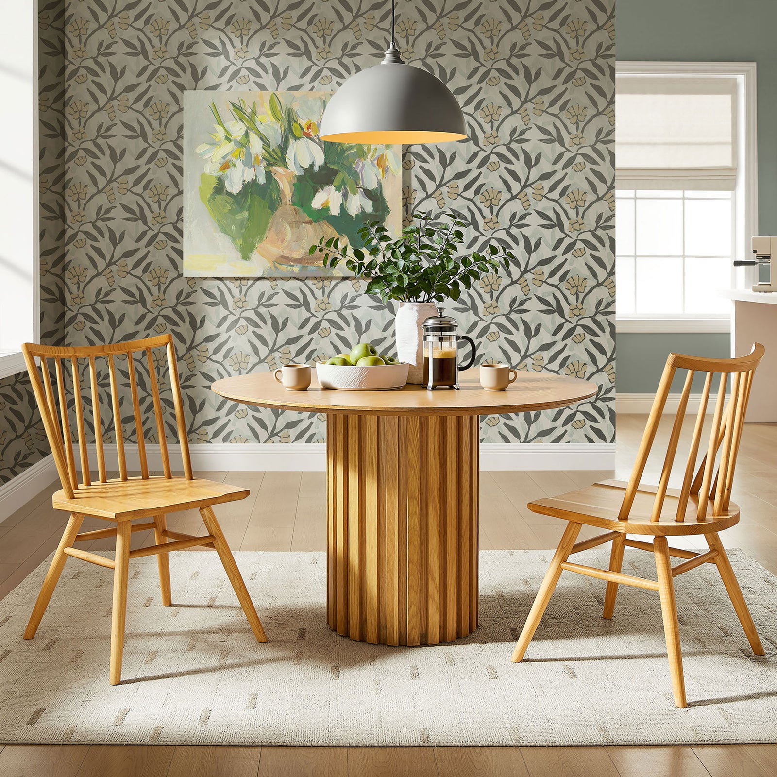 Set of two ash wood spindle back chairs arranged around a round pedestal table in a bright dining nook. || EEI-7482-ASH || front_angle_multi_room