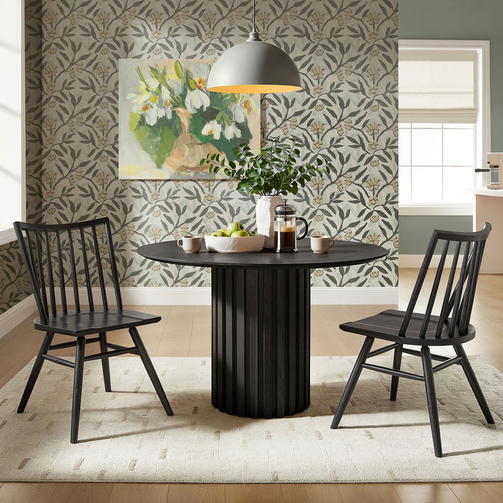Pair of black spindle back dining chairs arranged around a pedestal table in a bright, leafy dining room. || EEI-7482-BLK || front_angle_multi_room