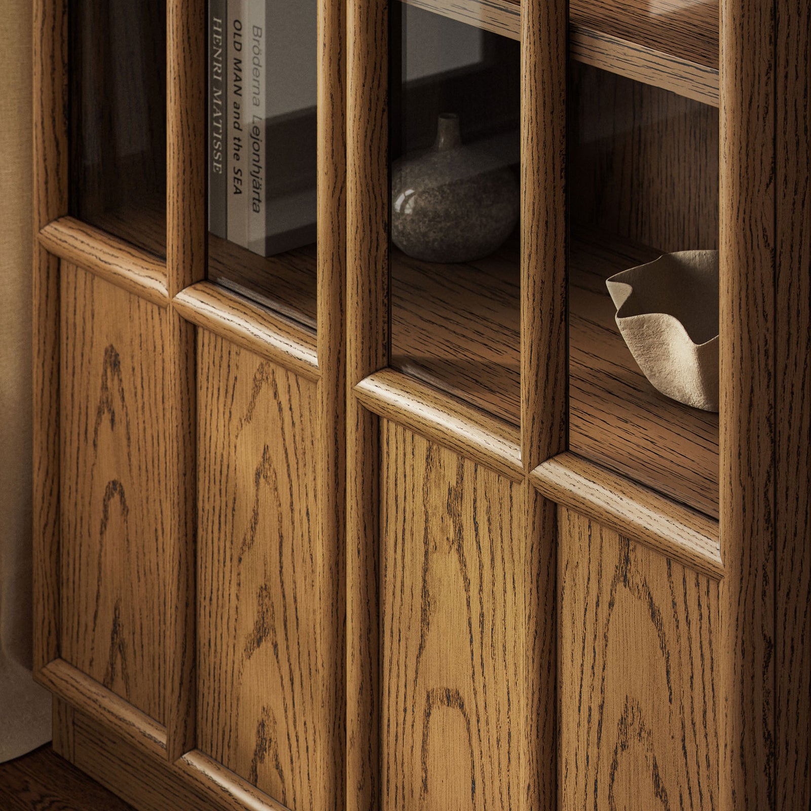 Lower oak cabinet panels and glass framing paired with cozy upholstery for a warm, layered room look || EEI-7484-OAK || detail_room