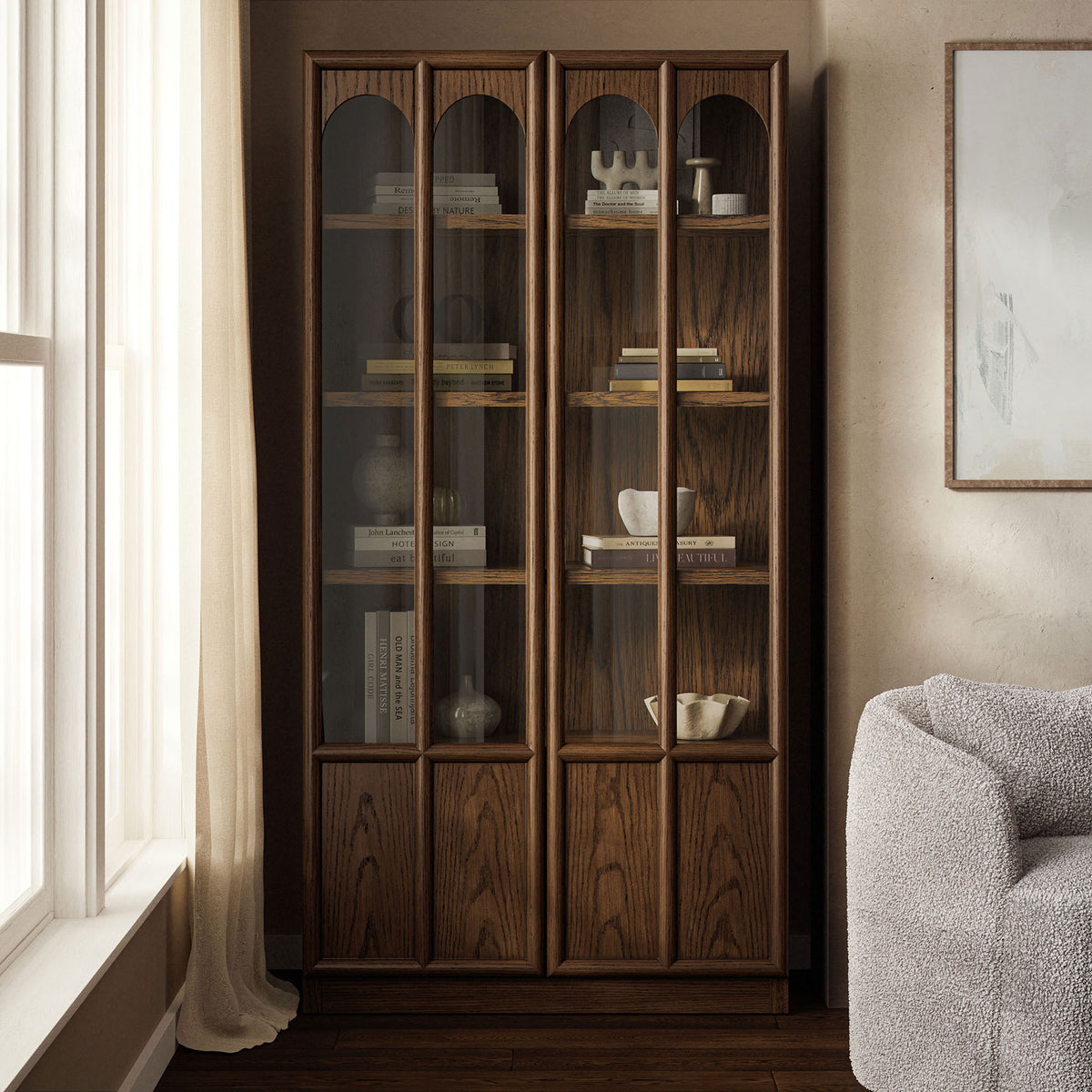 Walnut Anwen display cabinet arranged in a cozy room vignette with books and decor behind glass doors || EEI-7484-WAL || front_angle_room