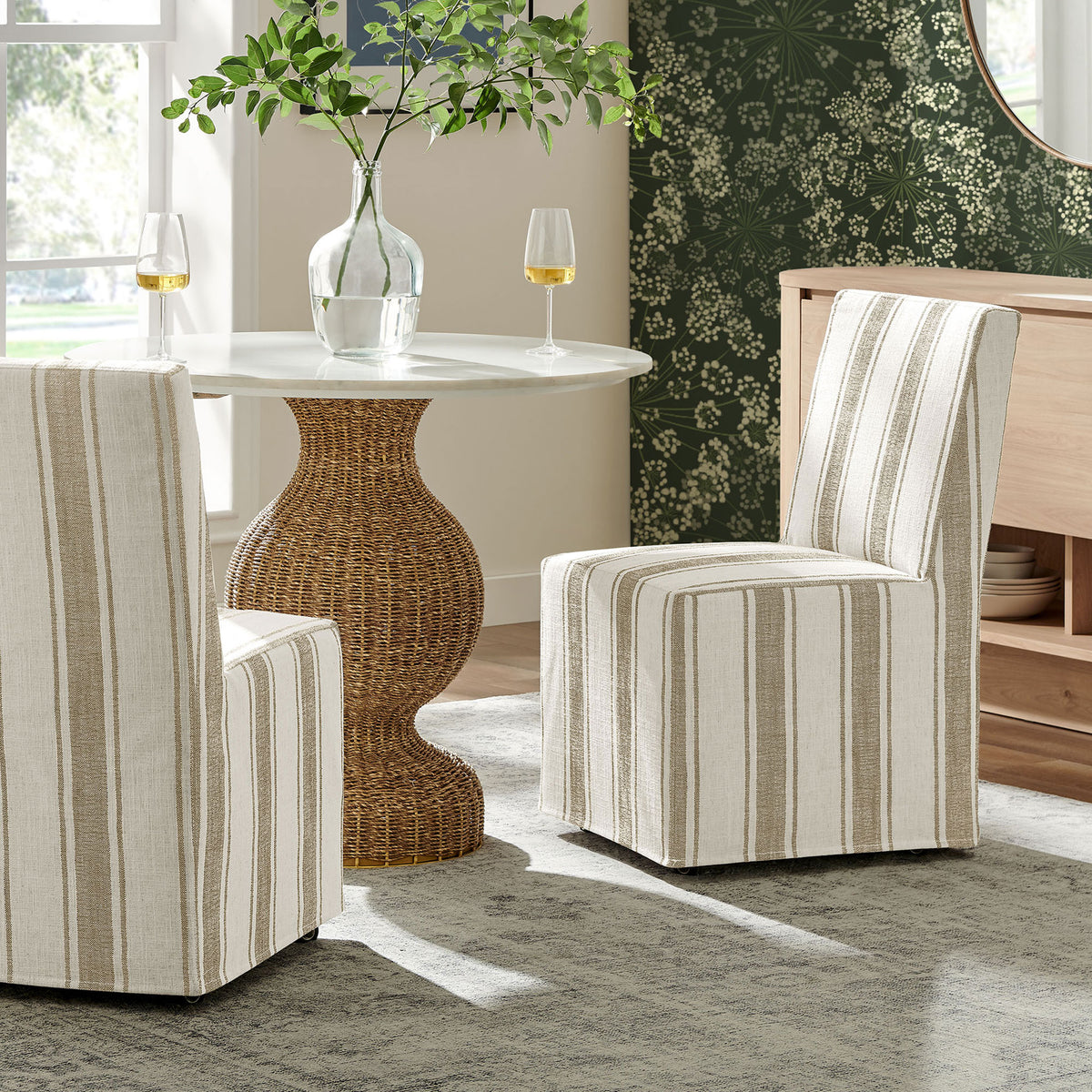 Pair of tan striped slipcovered dining chairs around a modern round table creating a relaxed gathering space || EEI-7486-TAN || front_angle_room