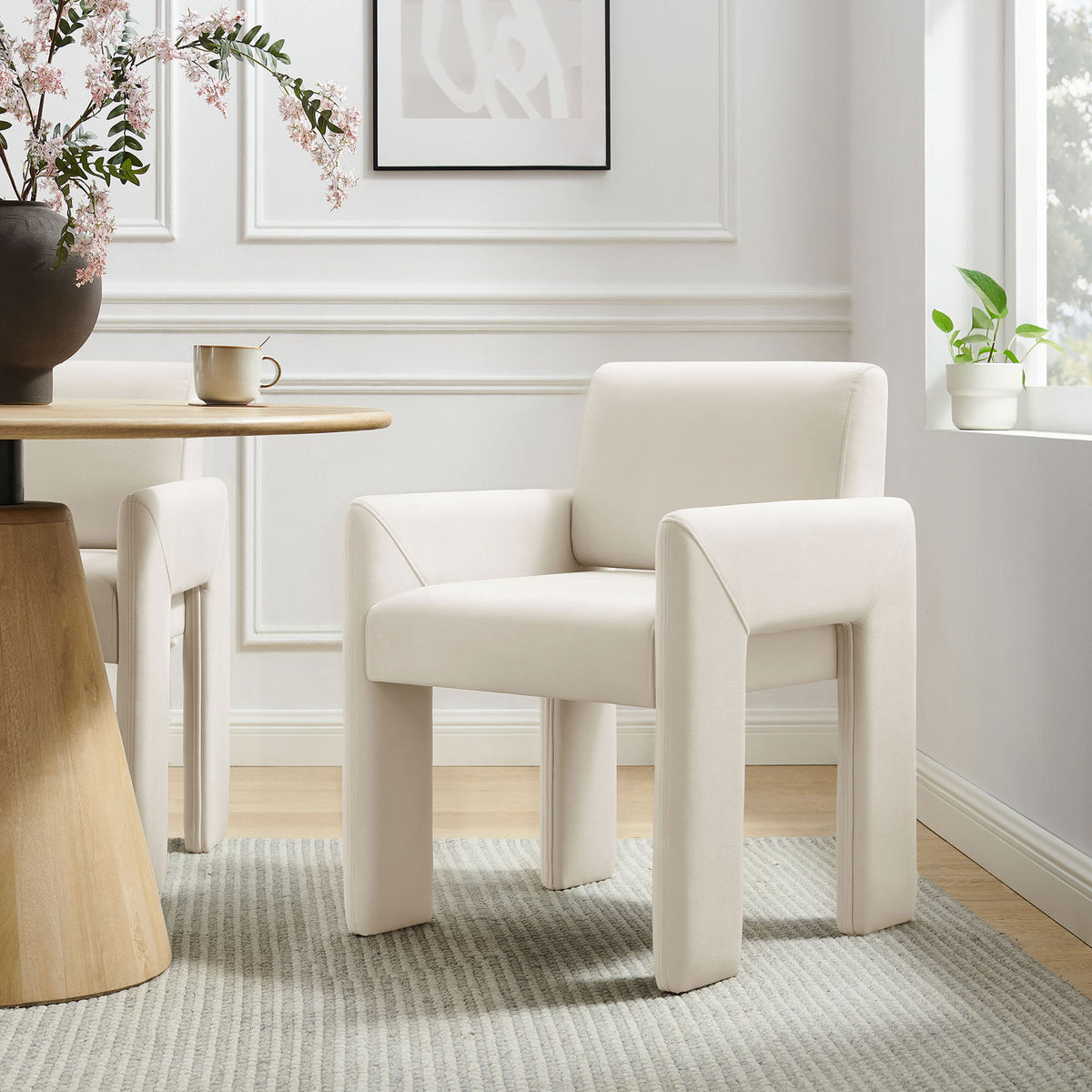 Velvet dining armchair styled at a round wood table, adding sculptural comfort to a light-filled dining room || EEI-7525-ALA || front_angle_room