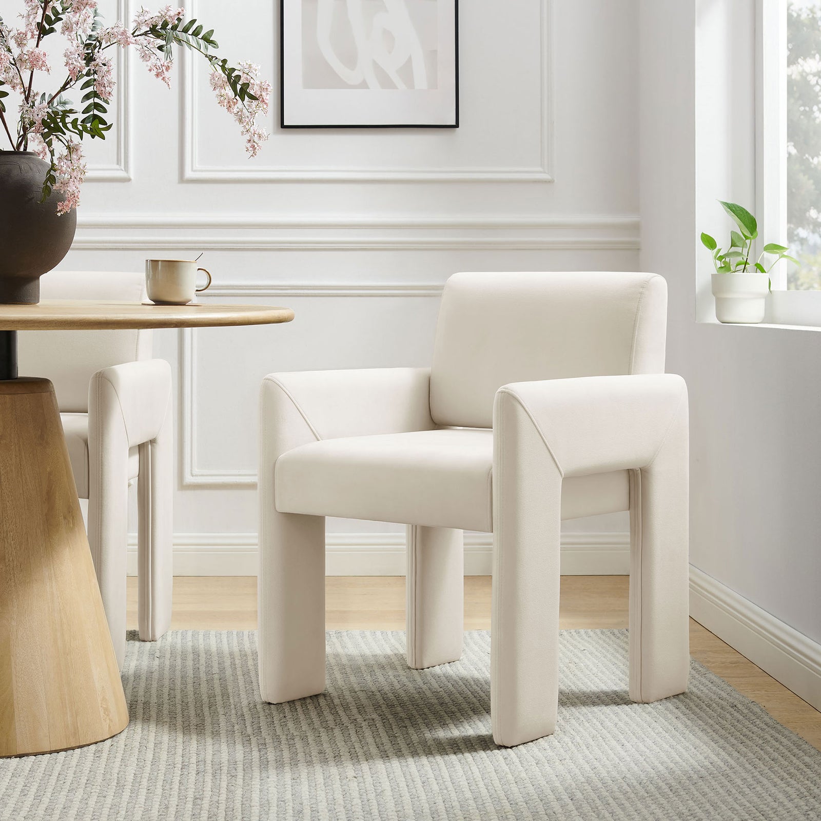 Velvet dining armchair styled at a round wood table, adding sculptural comfort to a light-filled dining room || EEI-7525-ALA || front_angle_room
