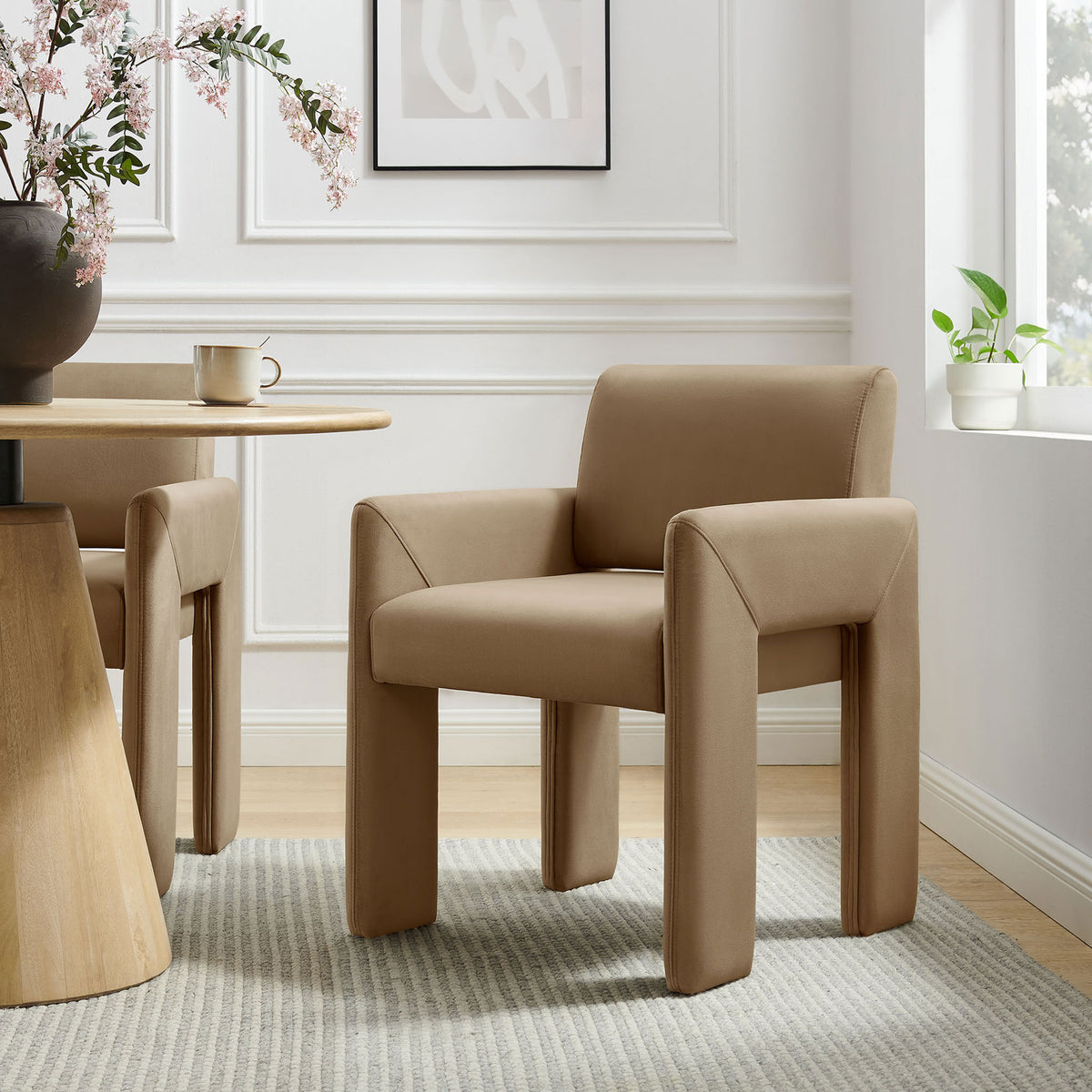 Taupe velvet dining armchair beside a round wood table for warm modern style || EEI-7525-TAU || front_angle_room