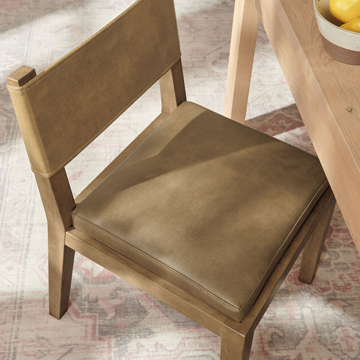 Calder toast vegan leather dining chair at the table, showing the plush seat cushion and smooth, textured upholstery || EEI-7527-TST || detail_room
