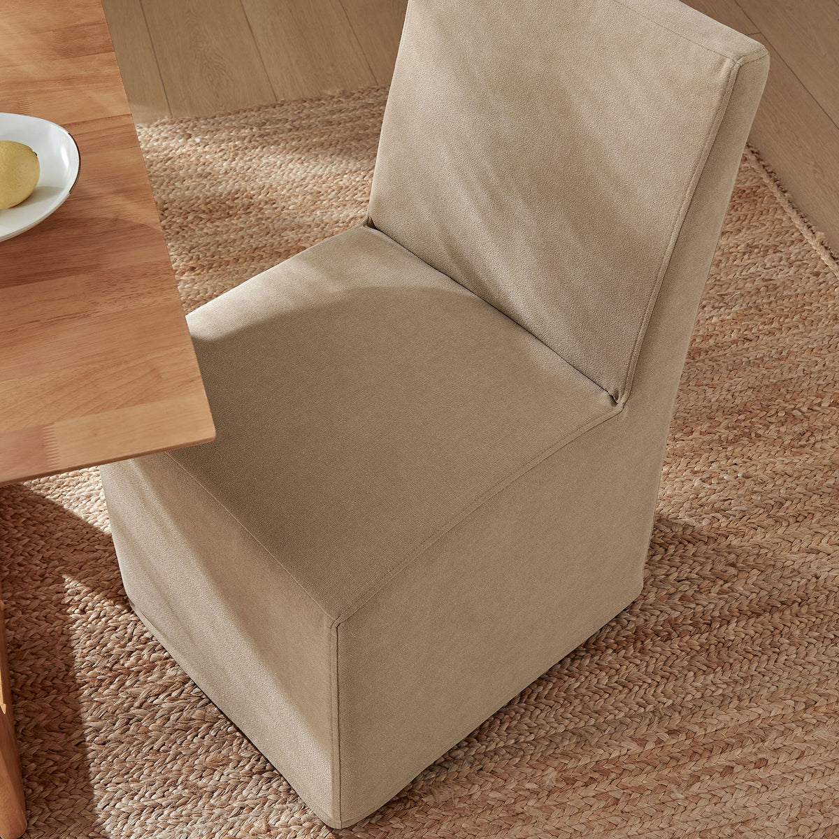 Almond linen-blend slipcovered dining chair tucks neatly at the table on a textured natural rug || EEI-7528-ALM || top_angle_room