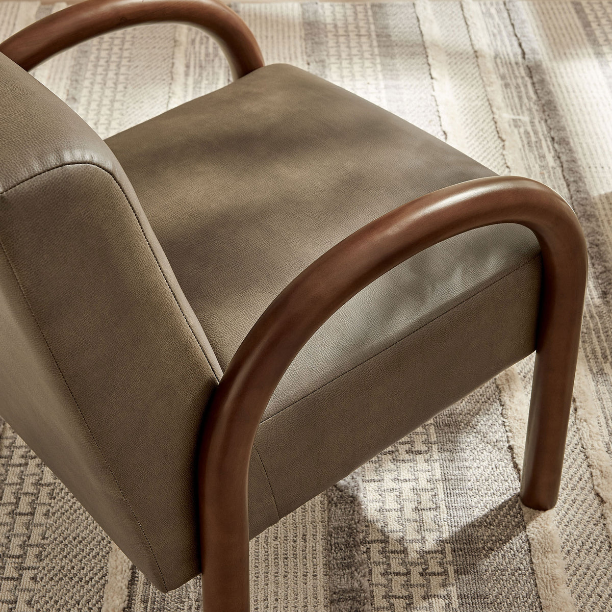 Textured faux leather and curved wood arm add warmth against a patterned area rug || EEI-7530-MUS || detail_room