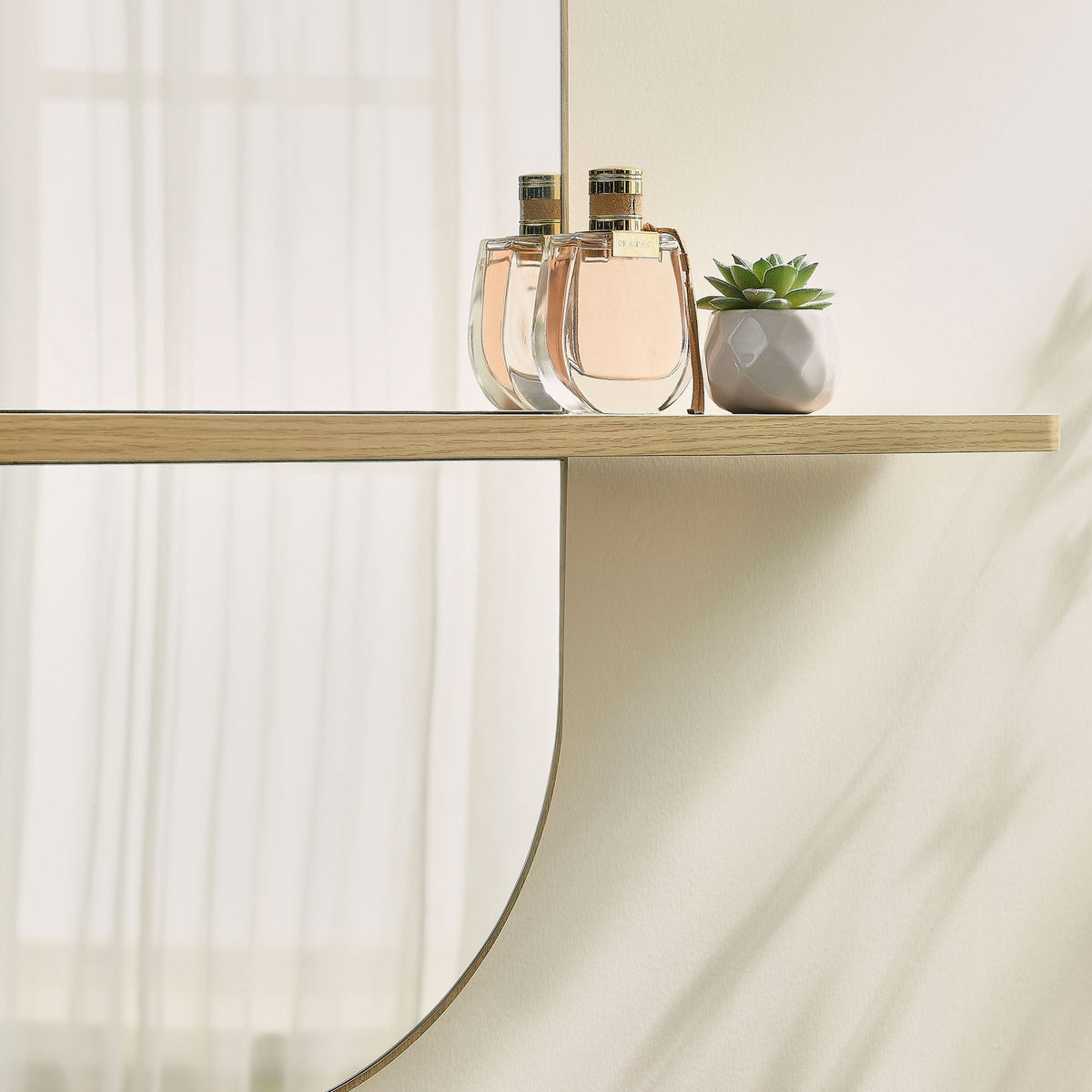 Large oak mirror shelf displaying perfume and a succulent against a softly lit wall. || EEI-7533-OAK || storage_room
