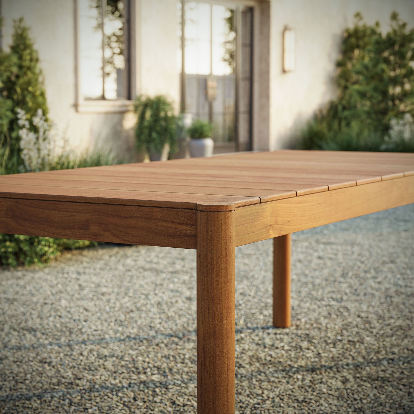 Natural teak Eleni dining table bringing warm coastal style to an outdoor gravel patio setting || EEI-7562-NAT || detail_room