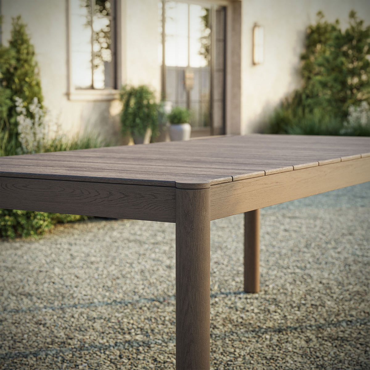 Weathered gray Eleni dining table adding rustic character to a relaxed open air gravel courtyard || EEI-7562-WGR || detail_room