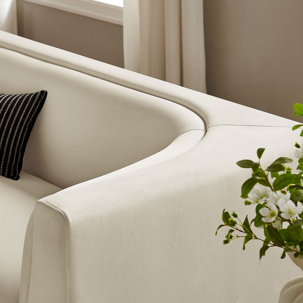 Curved back sofa in a bright living room, styled with greenery and a textured accent pillow. || EEI-7564-ALA || detail_room