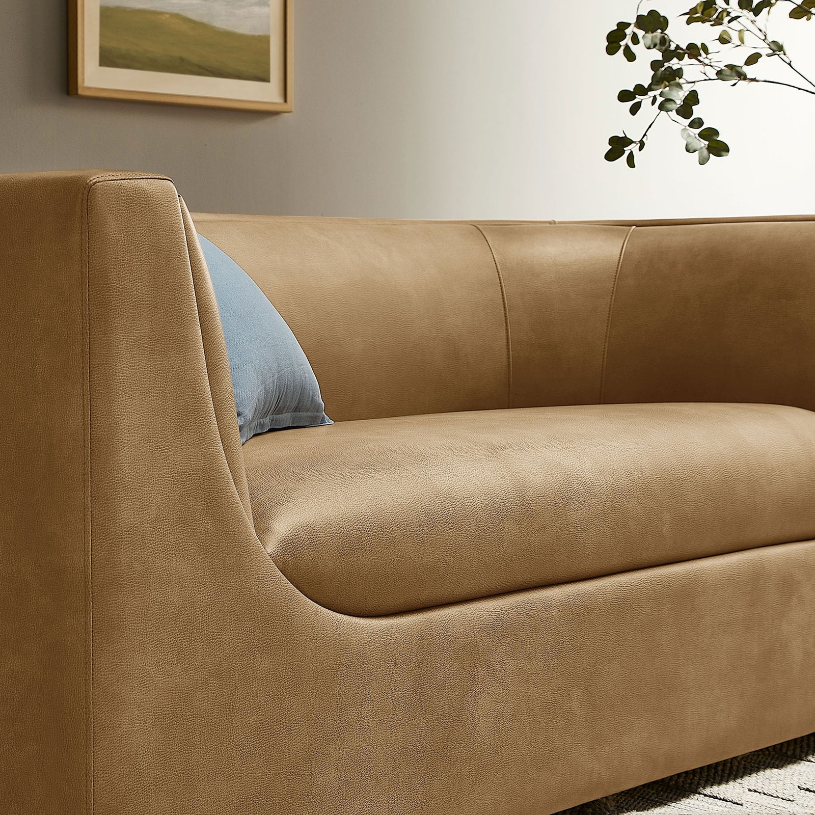 Toast vegan leather loveseat arm and seat styled with blue accent pillow in a cozy living room. || EEI-7568-TST || detail_room