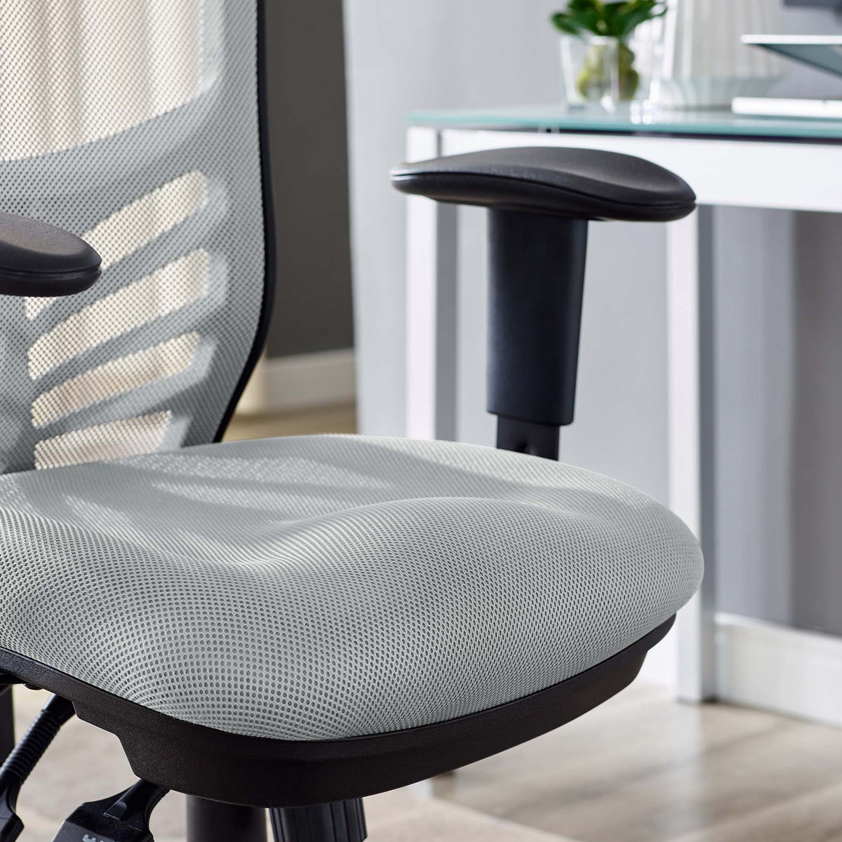 Textured gray mesh covers a thick cushion beside an adjustable black armrest