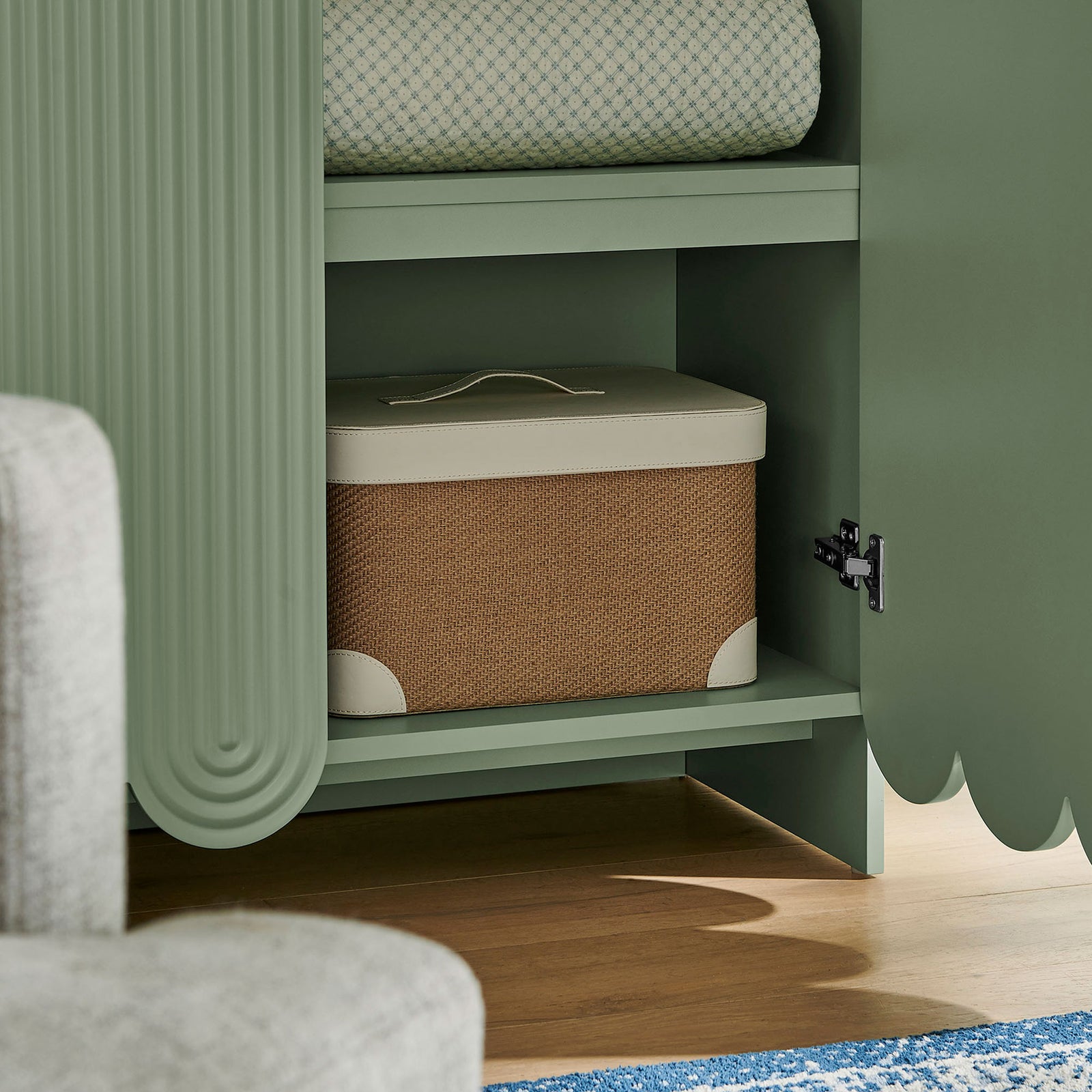 Styled interior of sage green cabinet shelf displaying a woven storage box and soft textiles || EEI-7570-SGE || storage_open_room