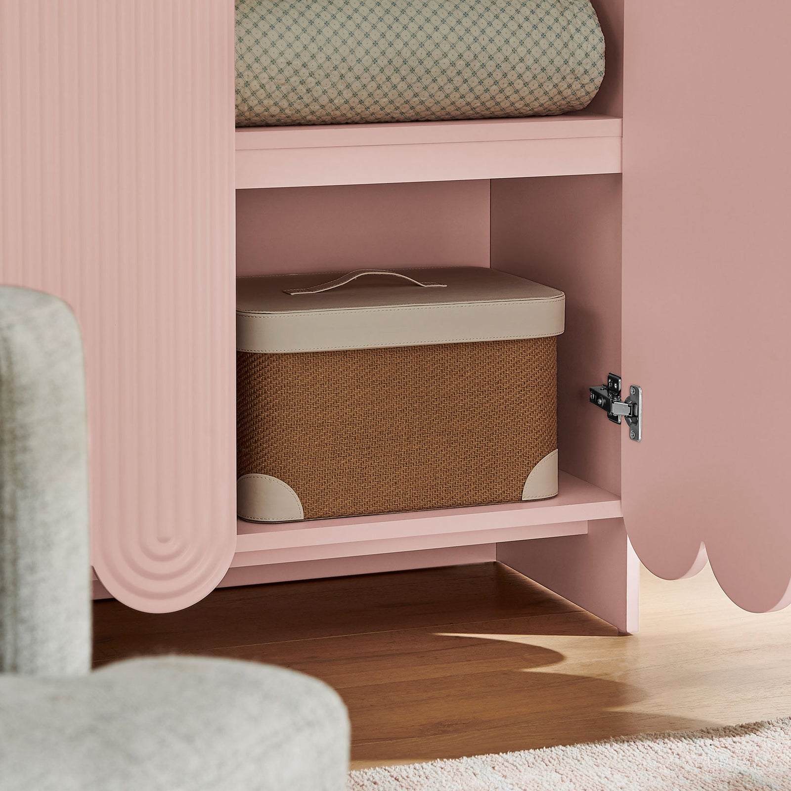 Styled interior of soft pink cabinet shelf featuring a woven storage box and cozy linens || EEI-7570-SPN || storage_open_room