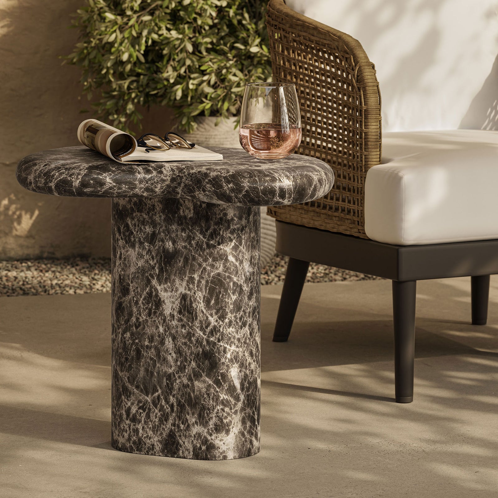 Kidney-shaped faux marble side table on a sunlit patio beside a cushioned chair, perfect for drinks and books || EEI-7572-EMP || front_angle_room