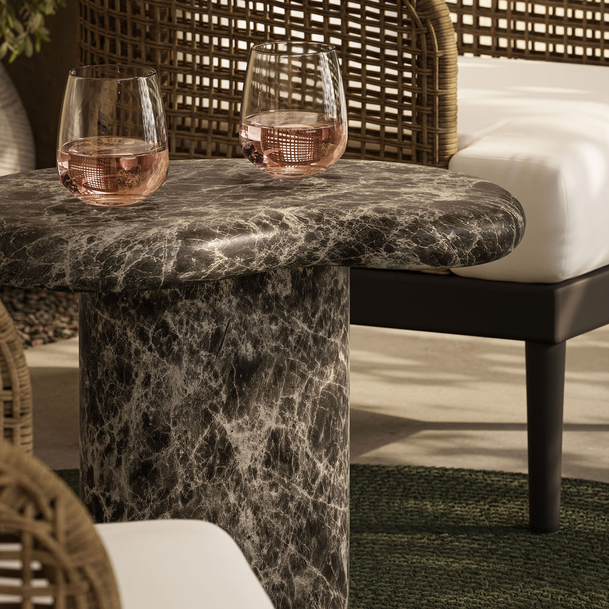 Emperador-look outdoor side table on a patio styled with rose wine glasses and woven lounge seating || EEI-7572-EMP || front_angle_room