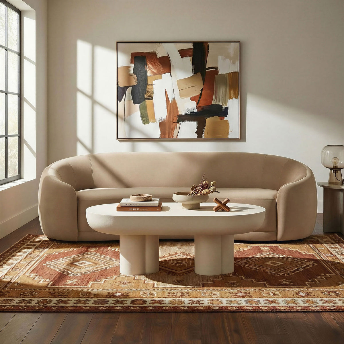 Taupe velvet curved sofa styled in a warm living room with abstract art, a modern coffee table, and patterned rug. || EEI-7581-TAU || front_room