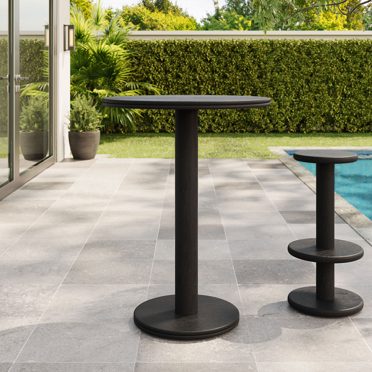 Black acacia bar table on patio with matching pedestal stool, perfect for casual poolside gatherings. || EEI-7585-BLK || front_angle_room